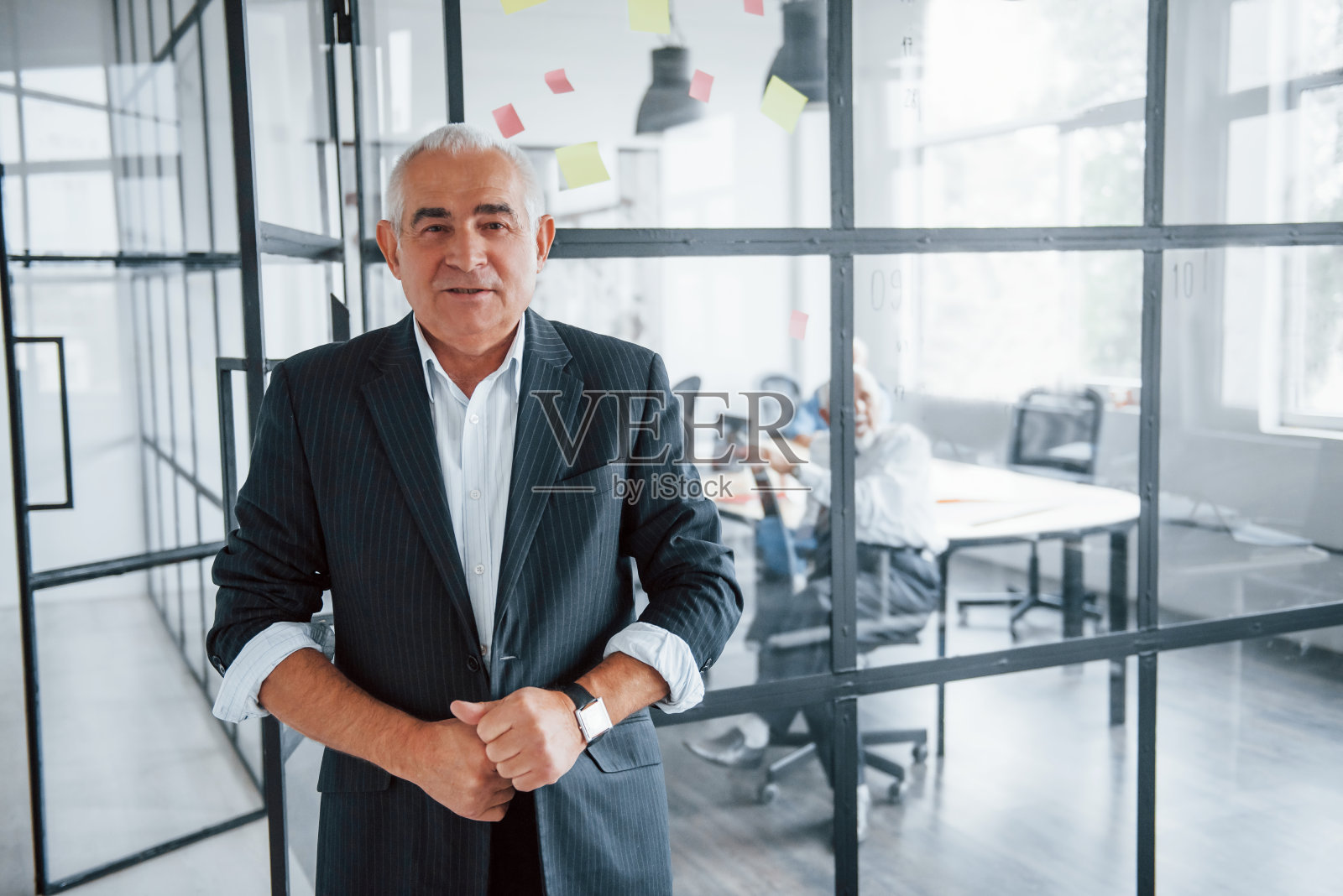 一位老人的肖像，他站在一群年老的商人建筑师面前，他们正在办公室开会照片摄影图片