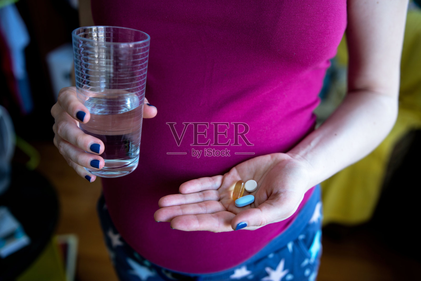 一个美丽的年轻孕妇在家里手里拿着维生素片和一杯水照片摄影图片