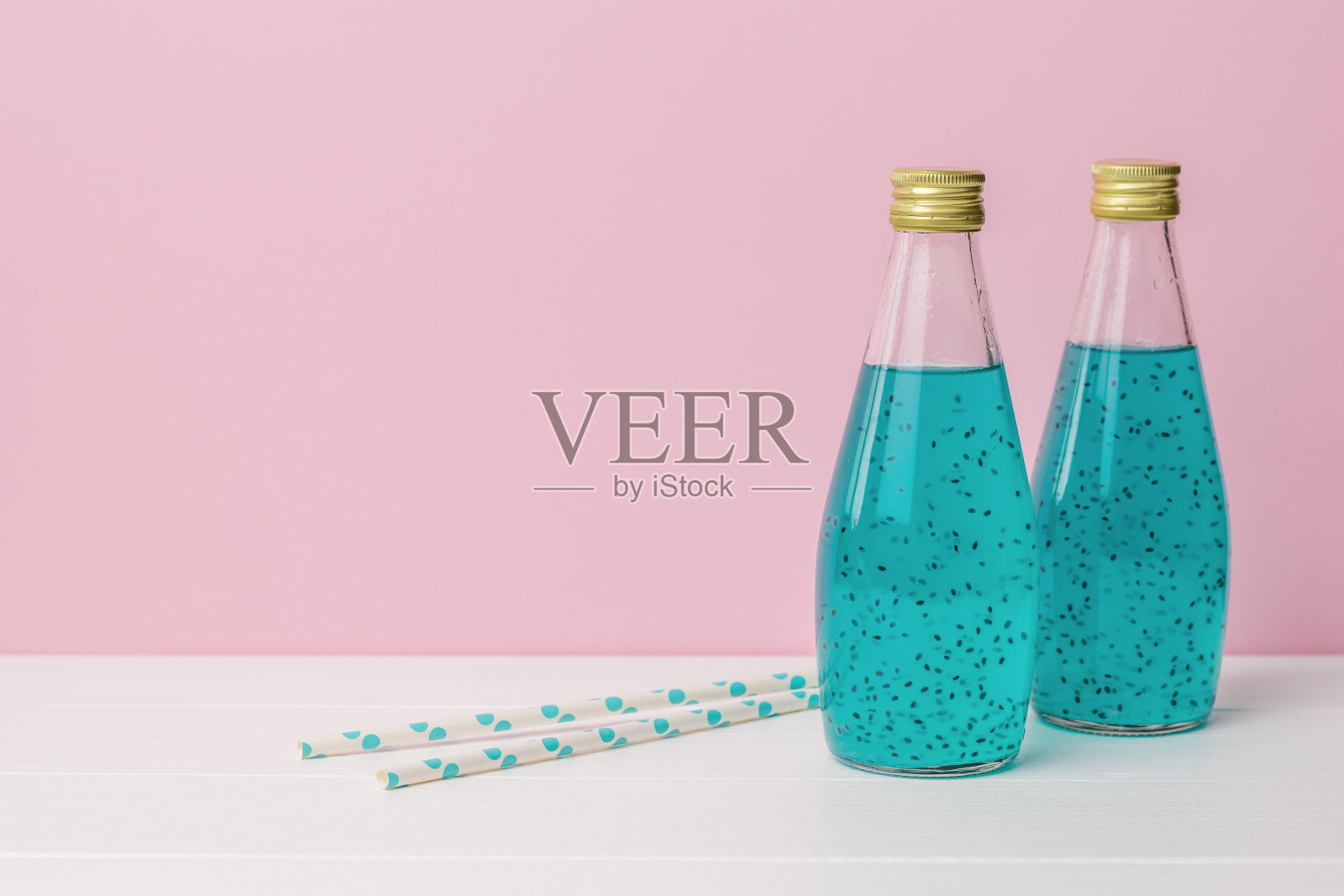 两个鸡尾酒管和两个鸡尾酒瓶在粉红色的背景。照片摄影图片