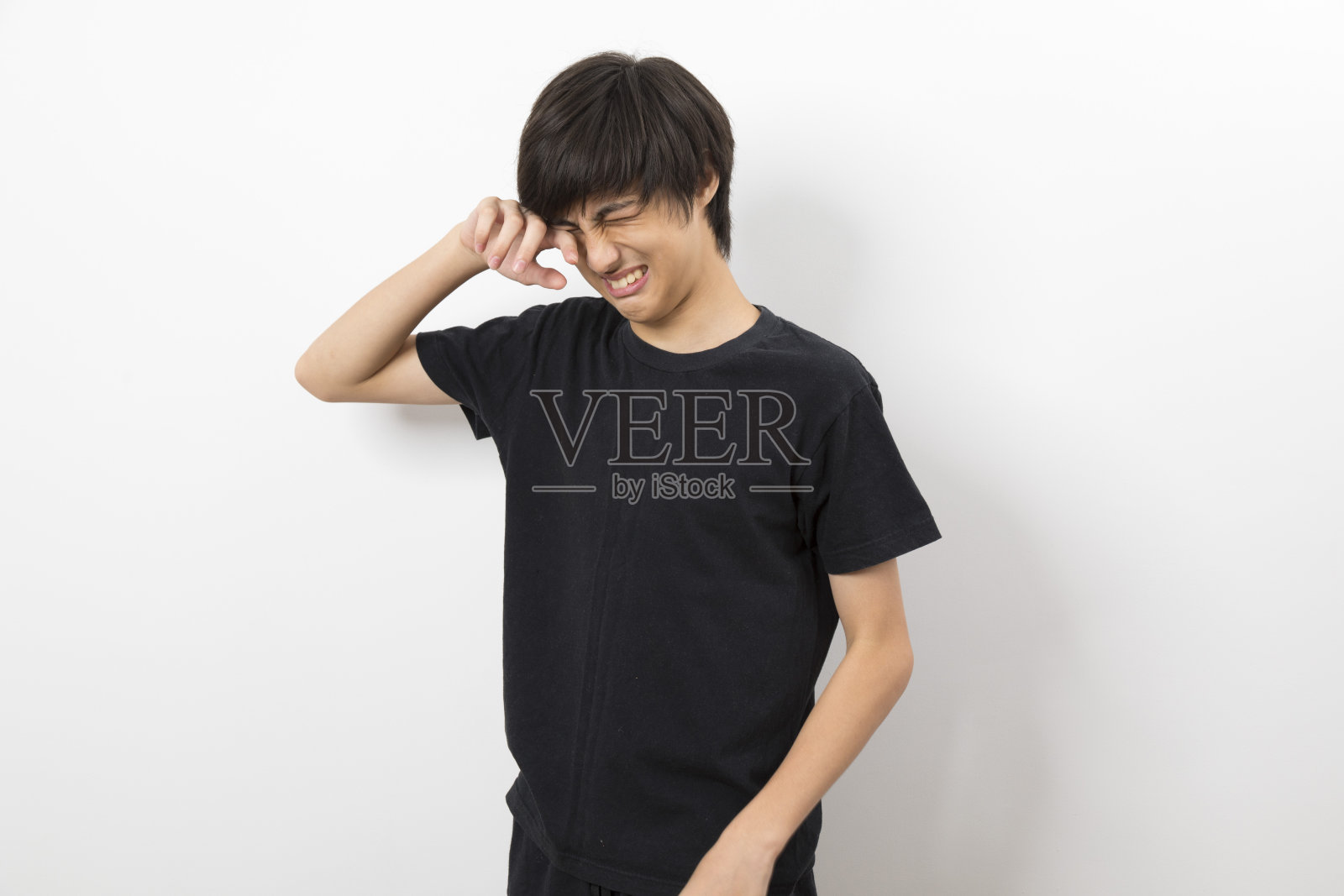 一个十几岁的男孩在白色背景上做鬼脸的肖像。照片摄影图片