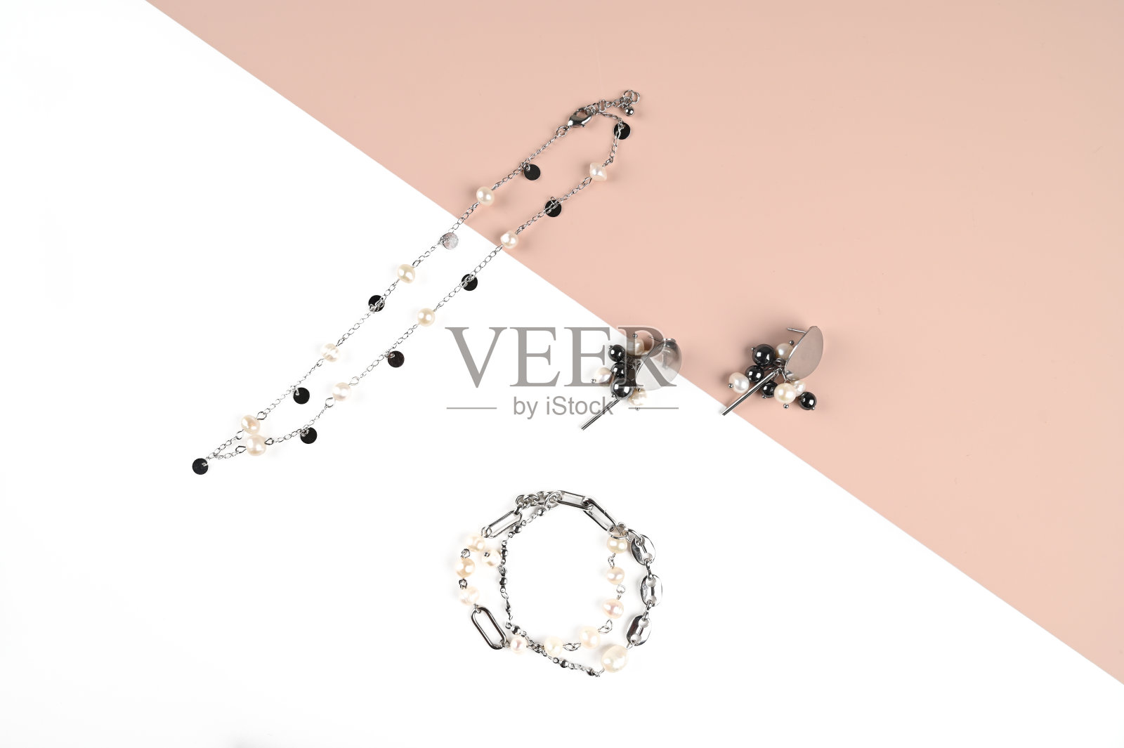 时髦的颈链，手镯和耳环与珍珠在一个白色和粉红色。时尚珠宝。俯视图照片摄影图片