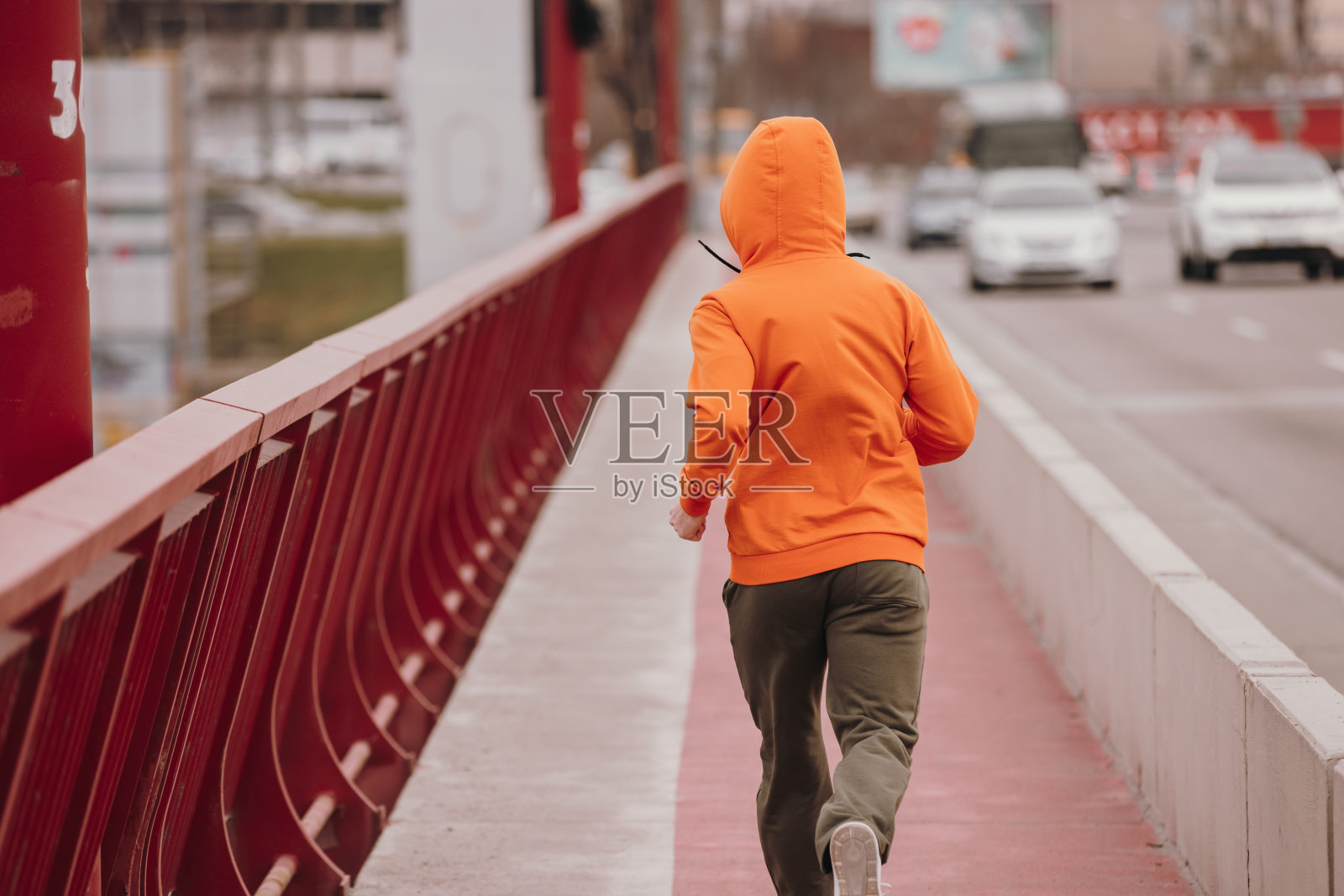 穿橙色连帽衫的男人在桥上奔跑，后视镜照片摄影图片