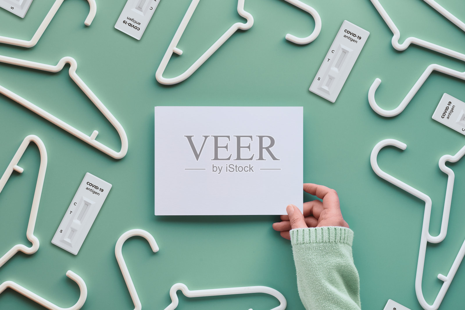 白色塑料衣架，手里拿着白纸和复印空间。俯视图平铺在时尚的淡绿色新薄荷背景，创造性的极简主义。销售理念，网上购物，价格实惠照片摄影图片