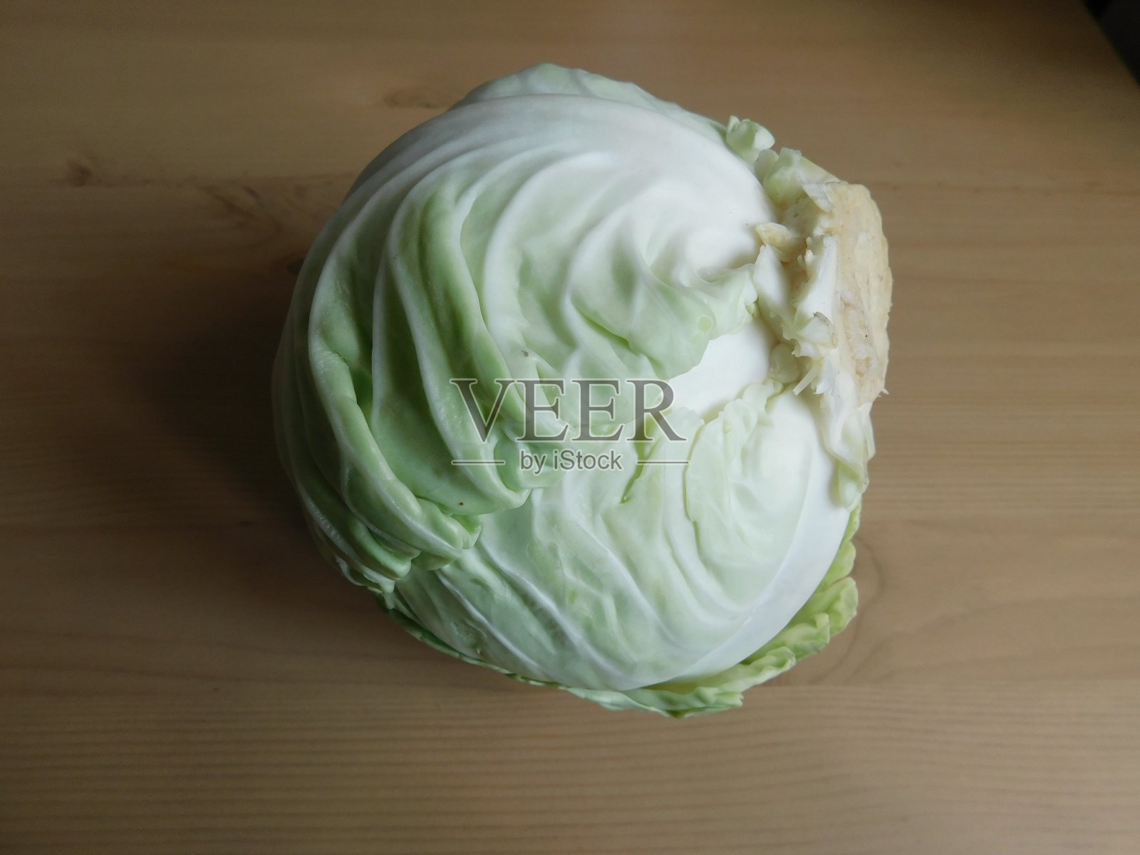 桌上放着一棵新鲜的白卷心菜。照片摄影图片