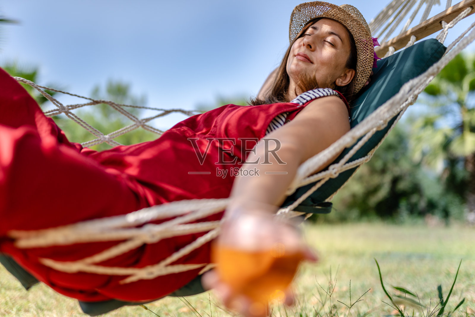 忙碌了一年之后，阳光明媚的一天，年轻女子在吊床上放松。照片摄影图片