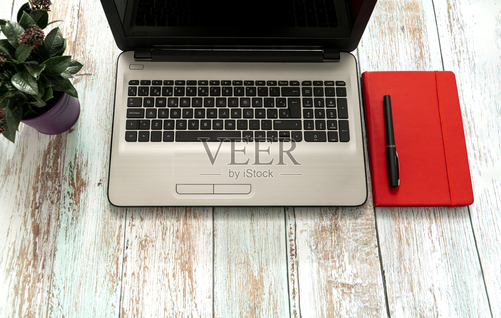 木质办公桌桌上有空白笔记本、笔、笔记本电脑等用品。顶视图与复制空间，平放。照片摄影图片