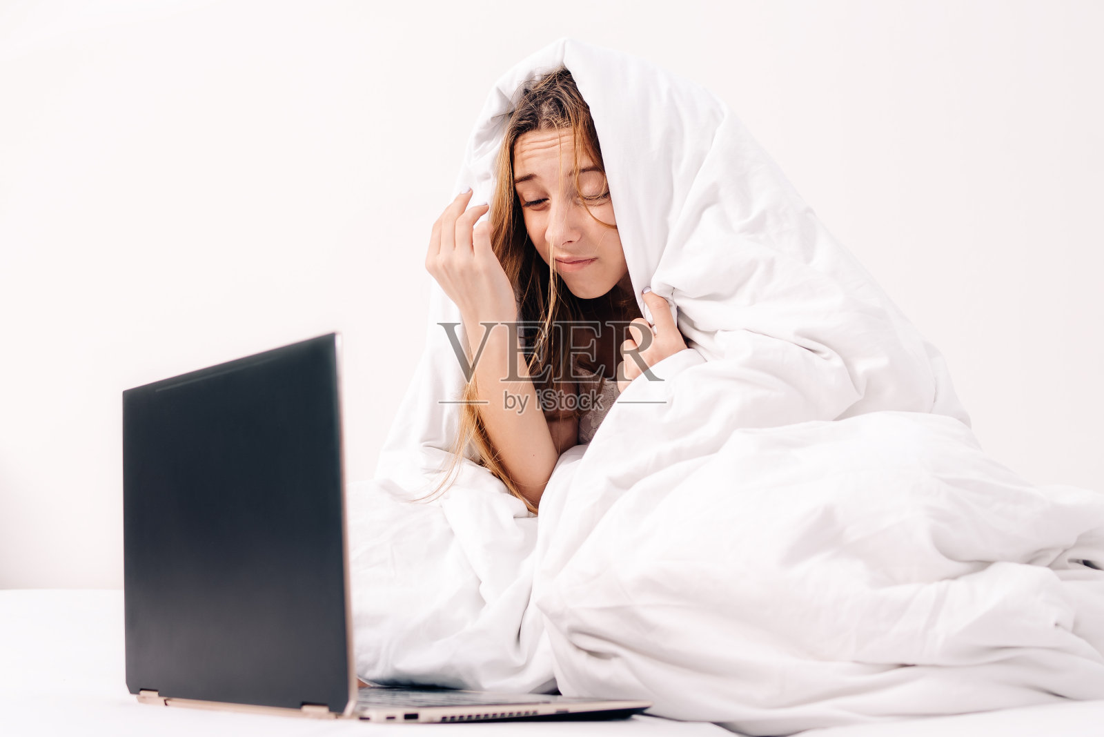 清晨，女孩在床上对着电脑工作，不想工作。距离工作。漂亮女人在床上摆弄电脑。照片摄影图片