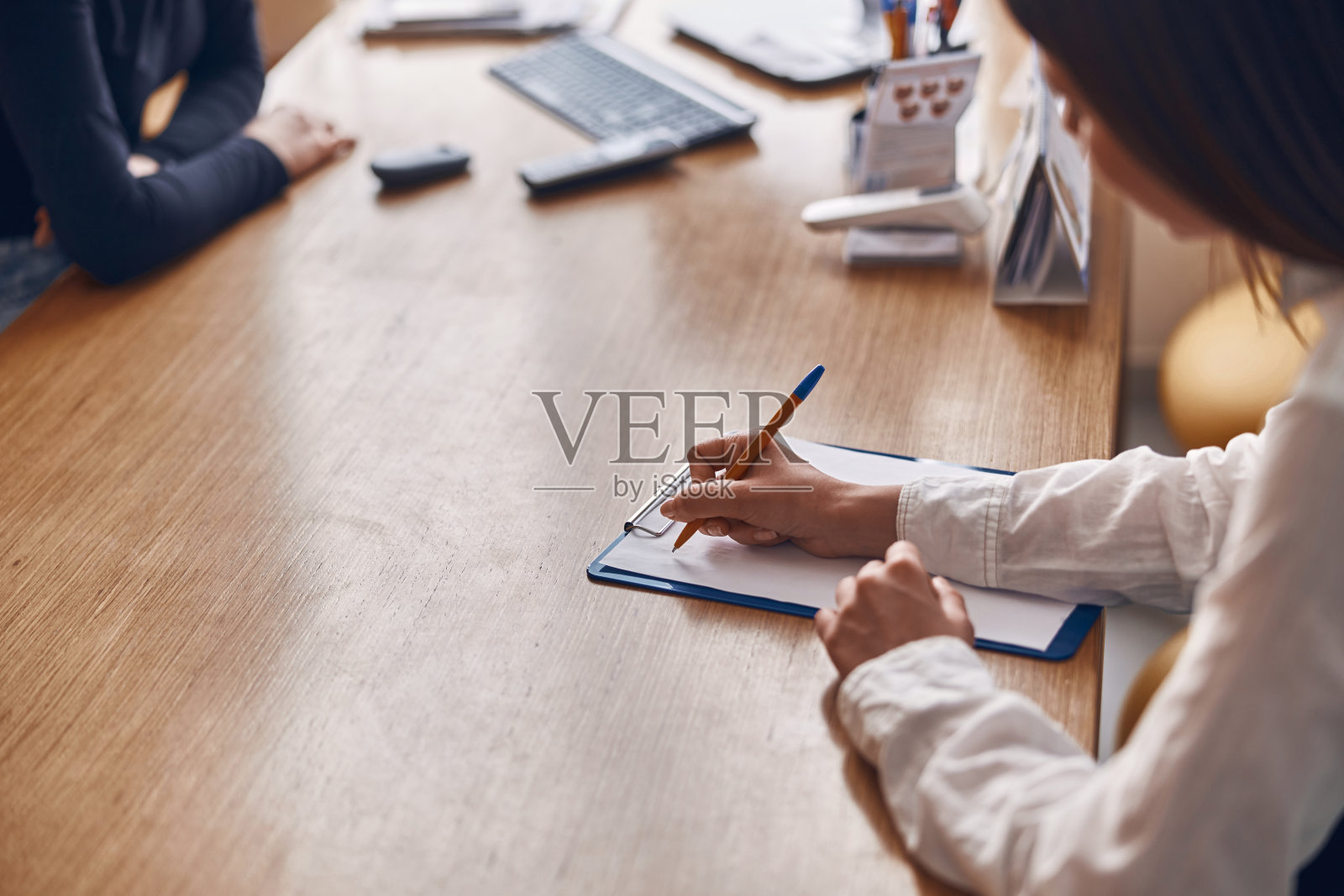 一位微笑的黑头发白种人女士正在填写诊所的接待文件照片摄影图片