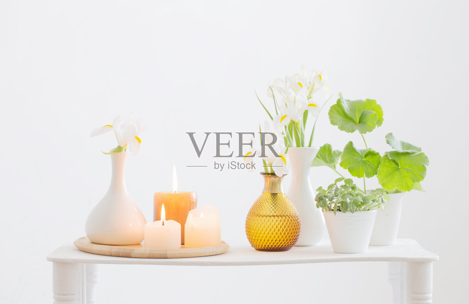 白色的室内木质架子上燃着蜡烛，盛开着春天的鲜花照片摄影图片