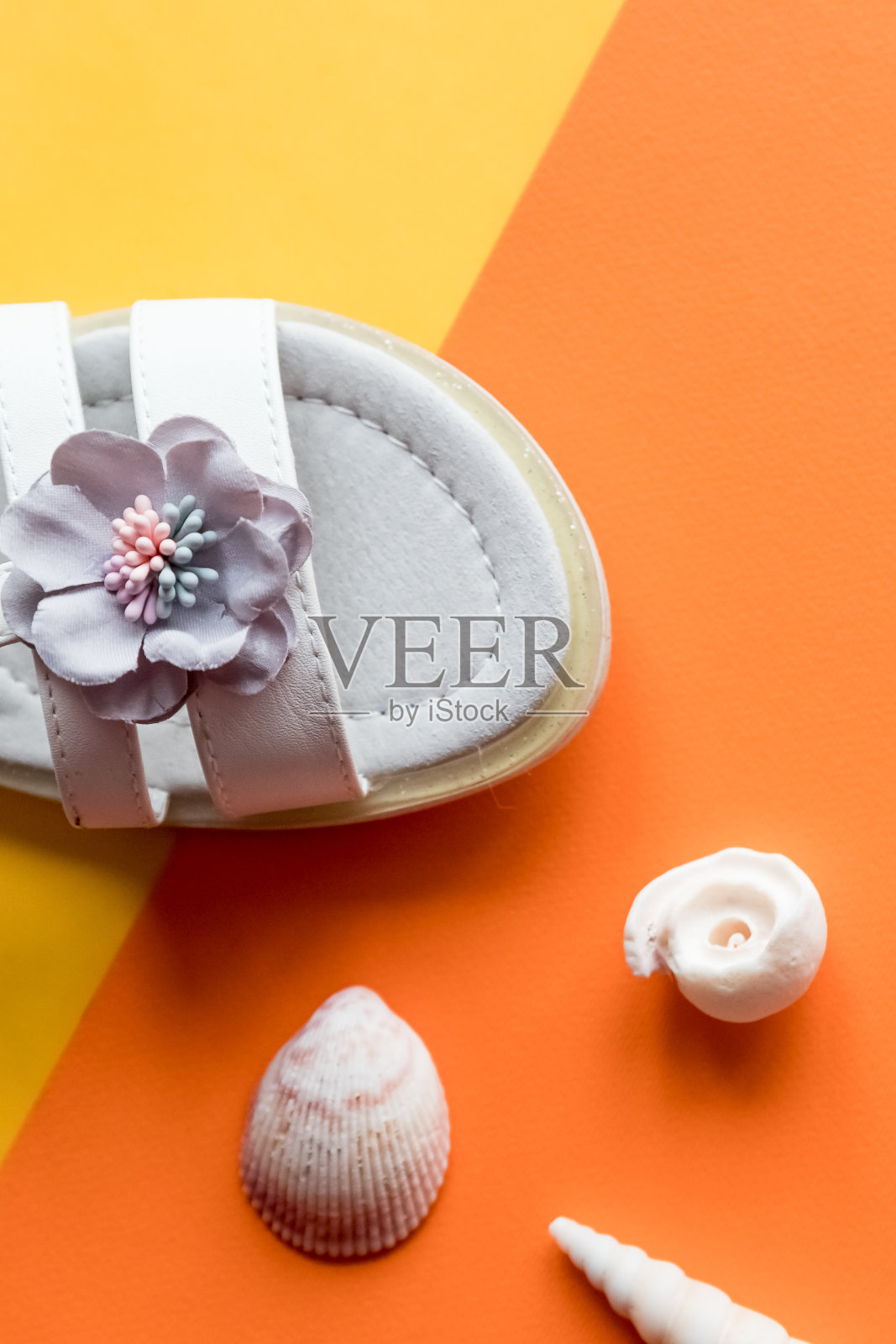 一双白色婴儿凉鞋的彩色背景，俯视图。时尚的皮革女孩凉鞋和贝壳，构成。舒适的皮革儿童夏季鞋。节日的概念照片摄影图片