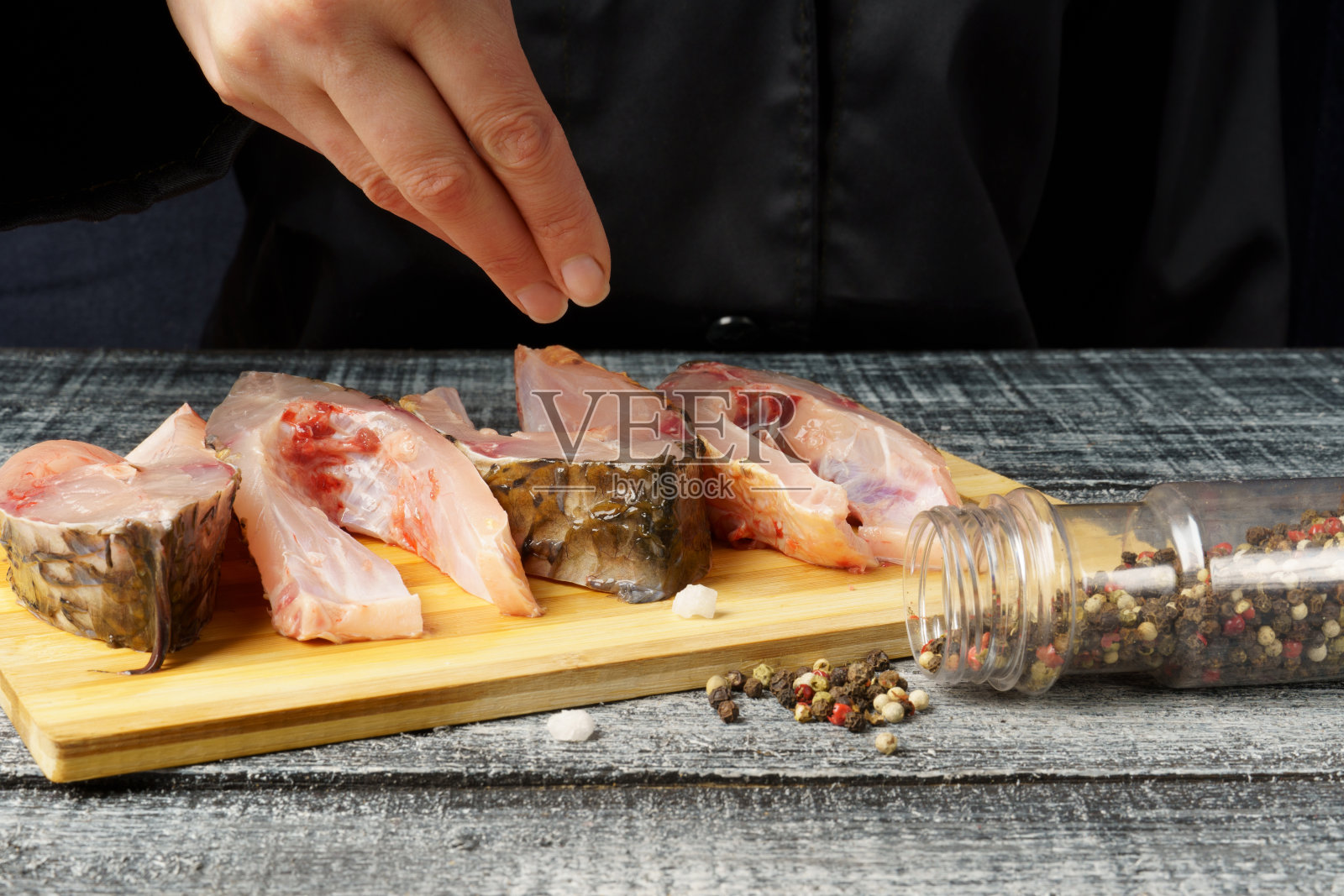 厨师用盐腌制鱼、鲤鱼。准备新鲜的鱼。水平照片与一个深黑色照片摄影图片