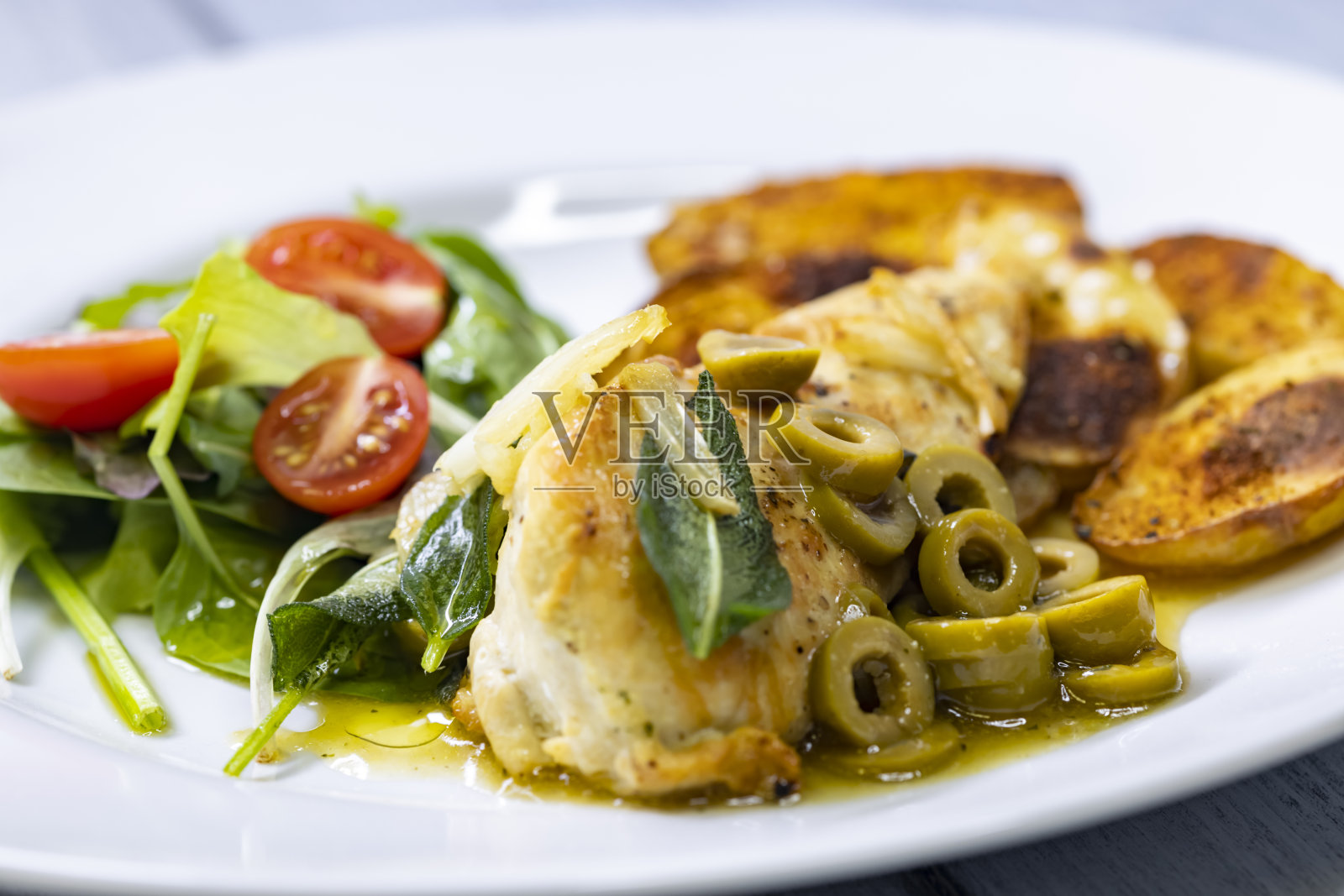 鼠尾草烤鸡胸肉，绿橄榄酱，沙拉和土豆照片摄影图片