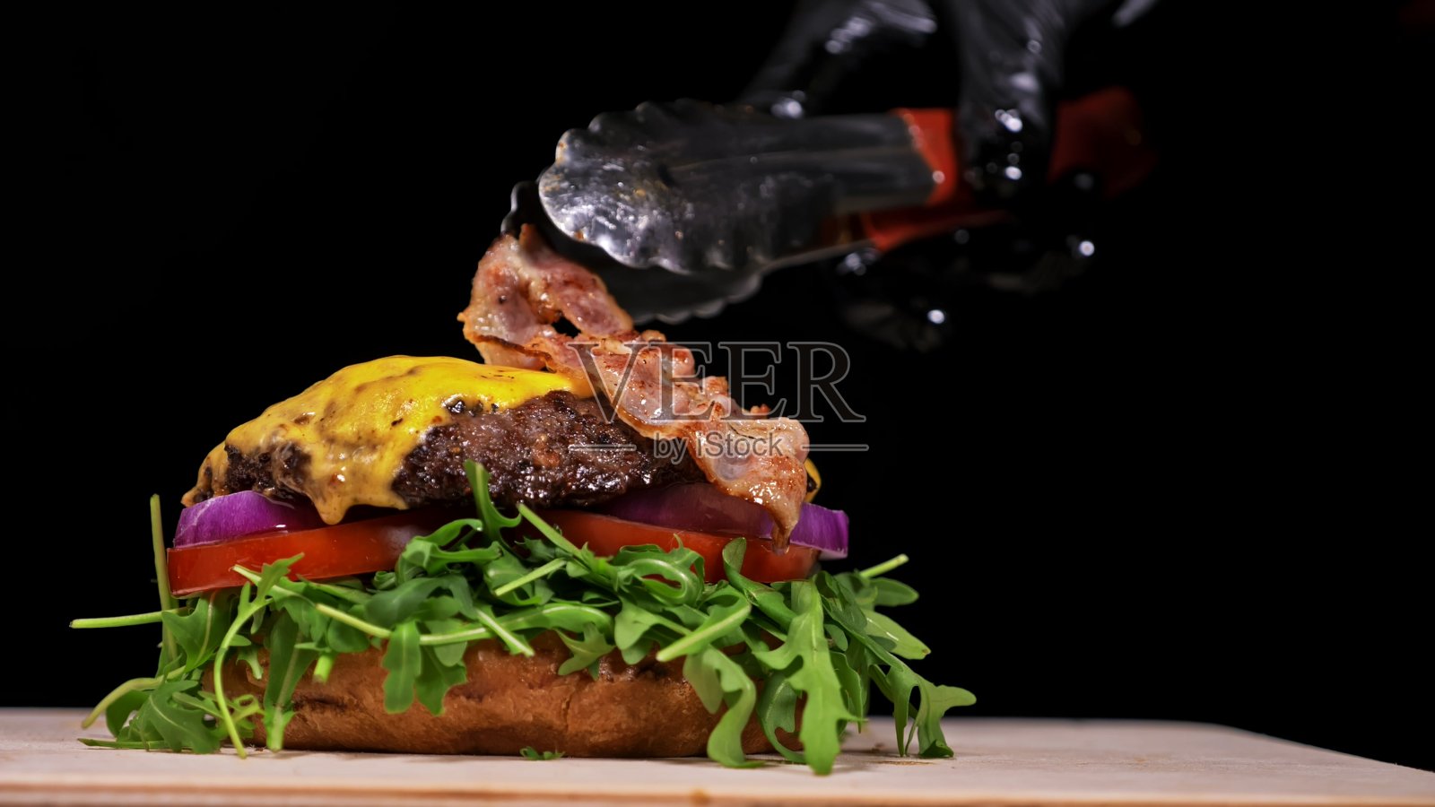 手工汉堡在黑色背景下烹饪。包括:酱汁，芝麻菜，番茄，洋葱，培根，葡萄干酱汁，乳清干酪，空气面包和大理石肉。照片摄影图片