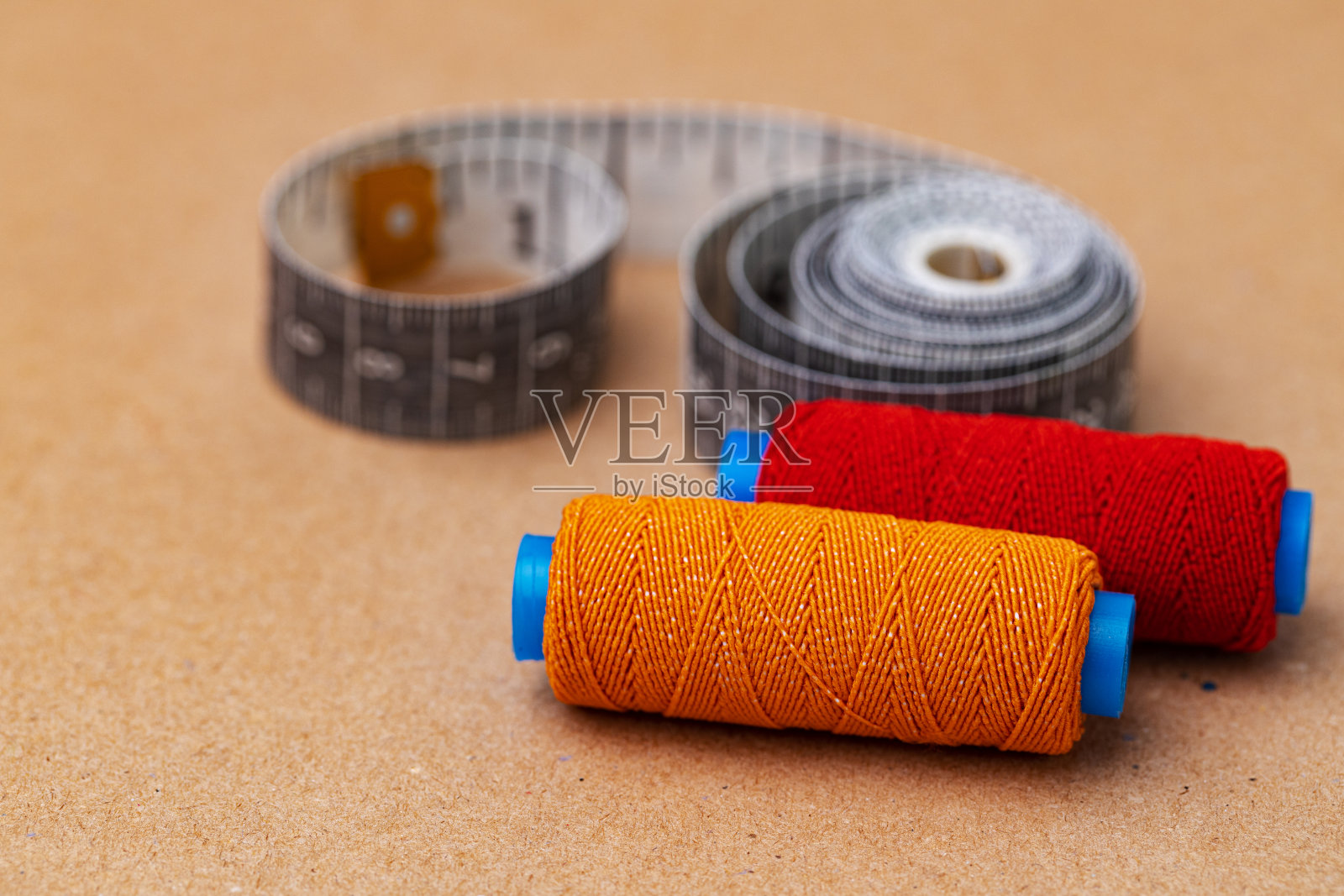 米色背景上的两个线轴和卷尺照片摄影图片