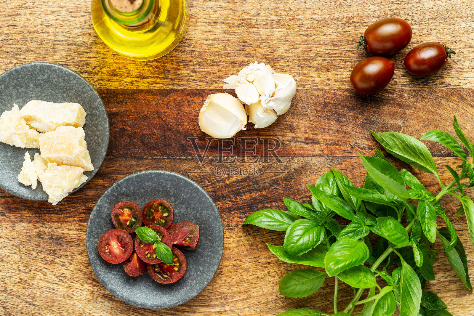 意大利菜配料:罗勒、西红柿、橄榄油和帕尔马干酪放在一个老式的砧板上。平躺，俯视图。照片摄影图片