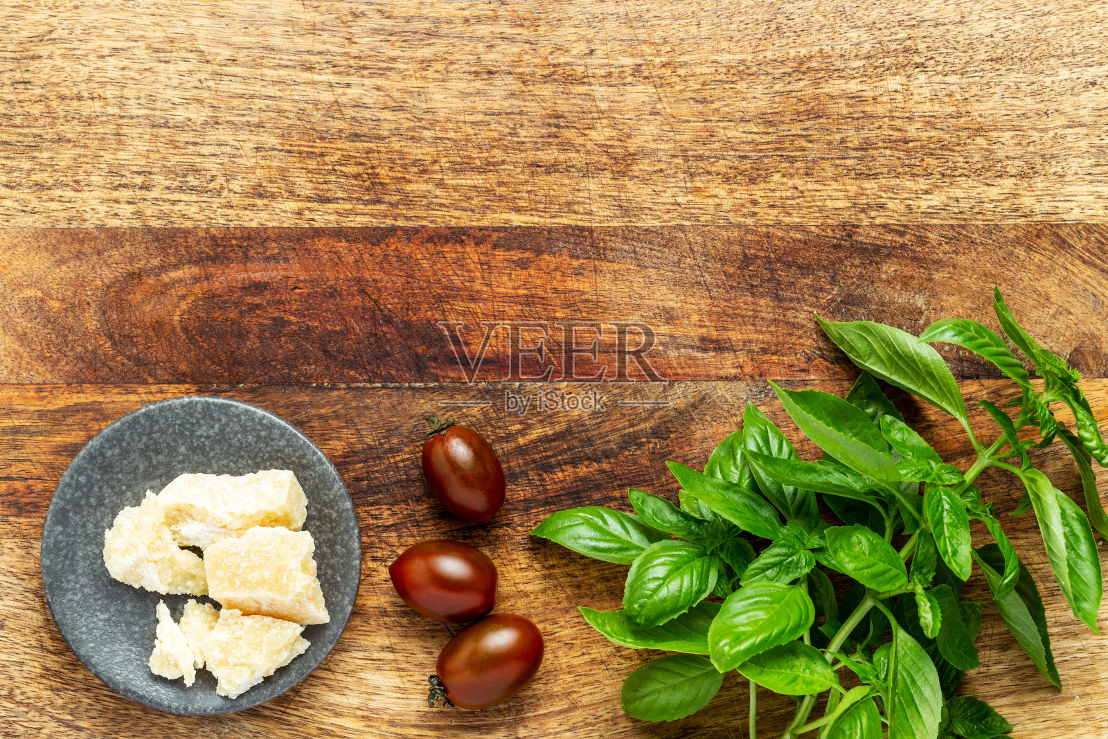 罗勒枝，整个西红柿和帕尔马干酪放在一个老式的砧板上。意大利沙拉的配料。平铺，俯视图与复制空间。照片摄影图片