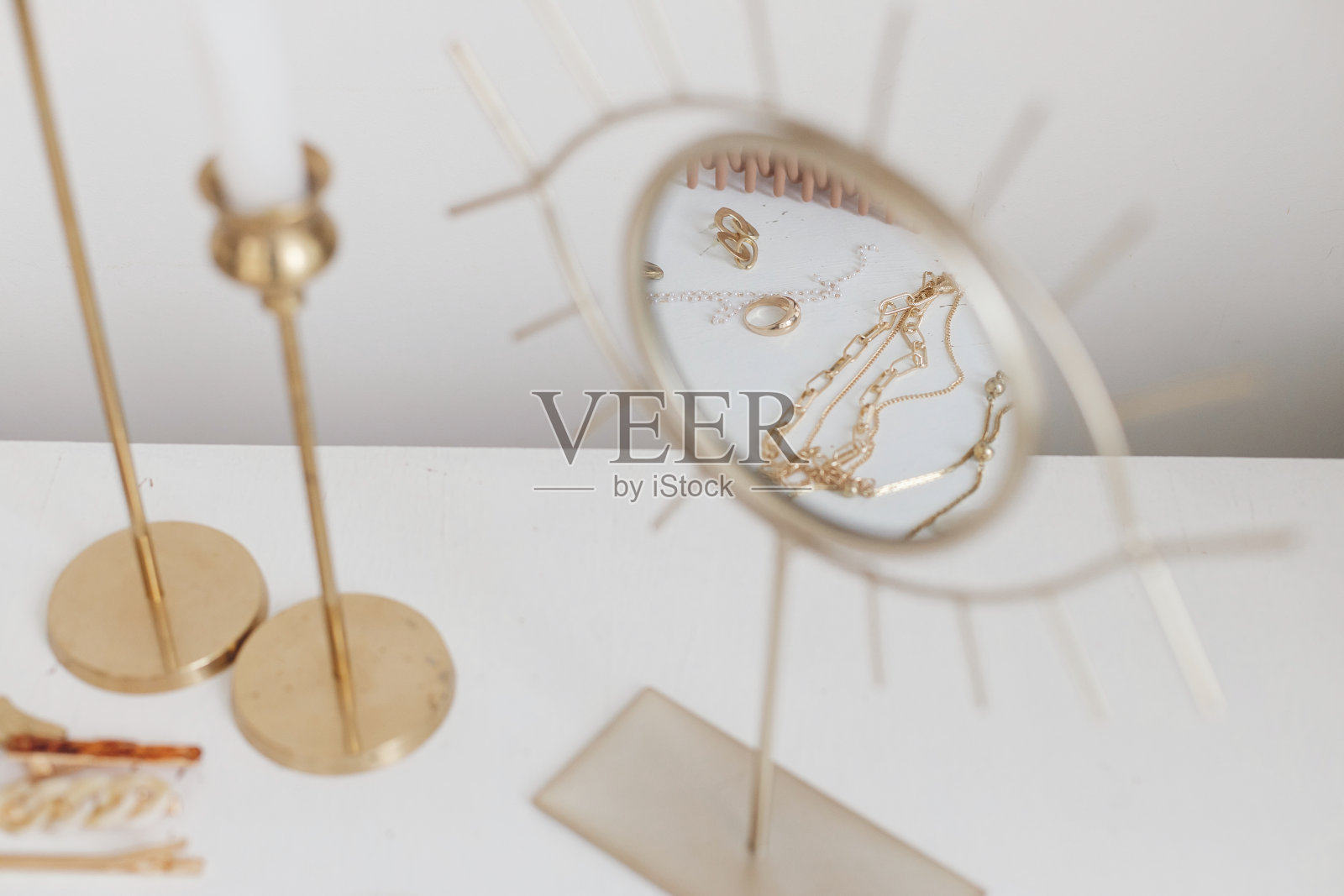 现代的金饰映照在波西米亚的镜子上，白色的桌子上放着复古的蜡烛。配件照片摄影图片