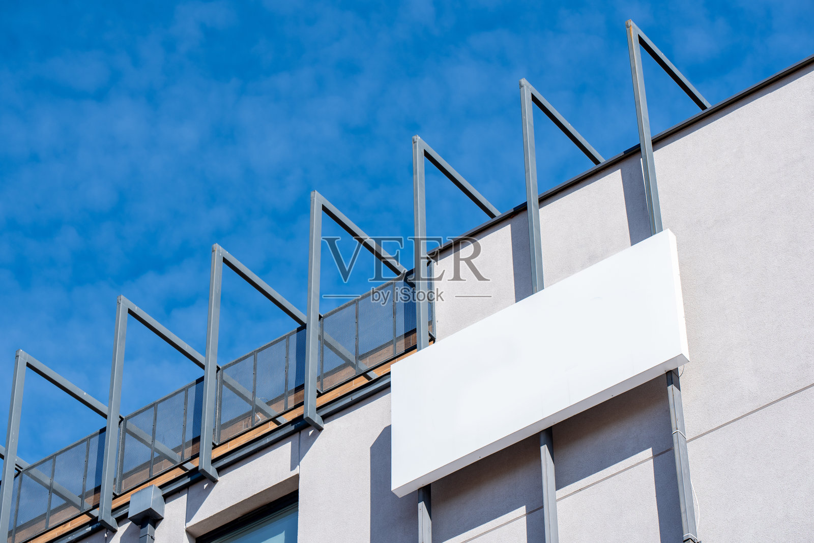 在阳光明媚的日子里，建筑正面的白色空白金属广告牌上有公司的标识照片摄影图片