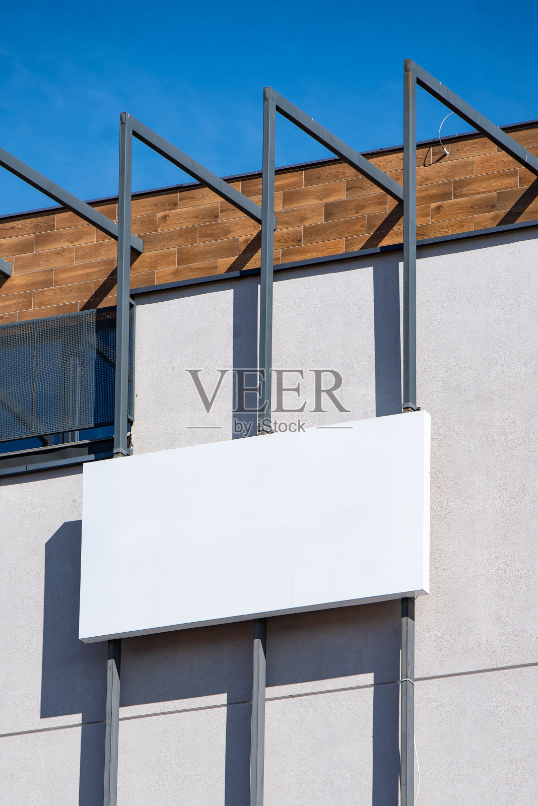 在阳光明媚的日子里，建筑正面的白色空白金属广告牌上有公司的标识照片摄影图片
