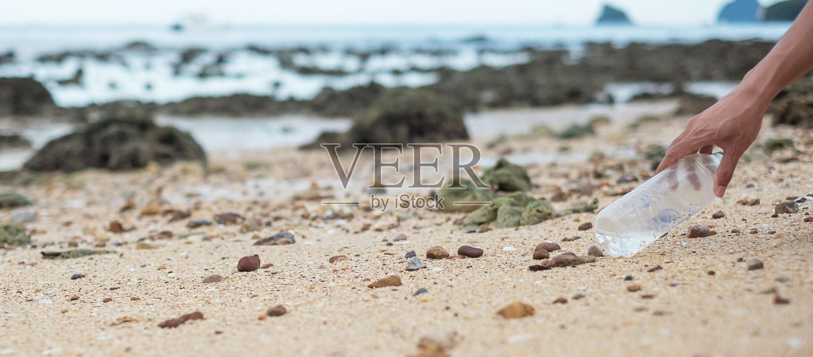 志愿者在海滩上用手捡垃圾，塑料瓶垃圾。生态学、环境、污染和生态问题的概念照片摄影图片