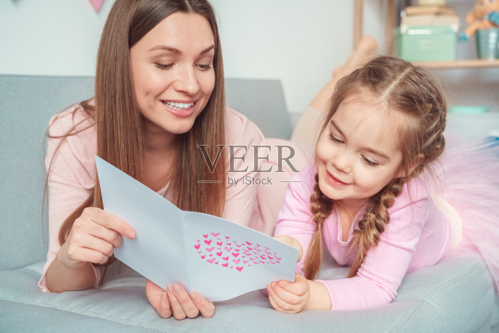 周末妈妈和女儿一起在家沙发上看书祝贺照片摄影图片