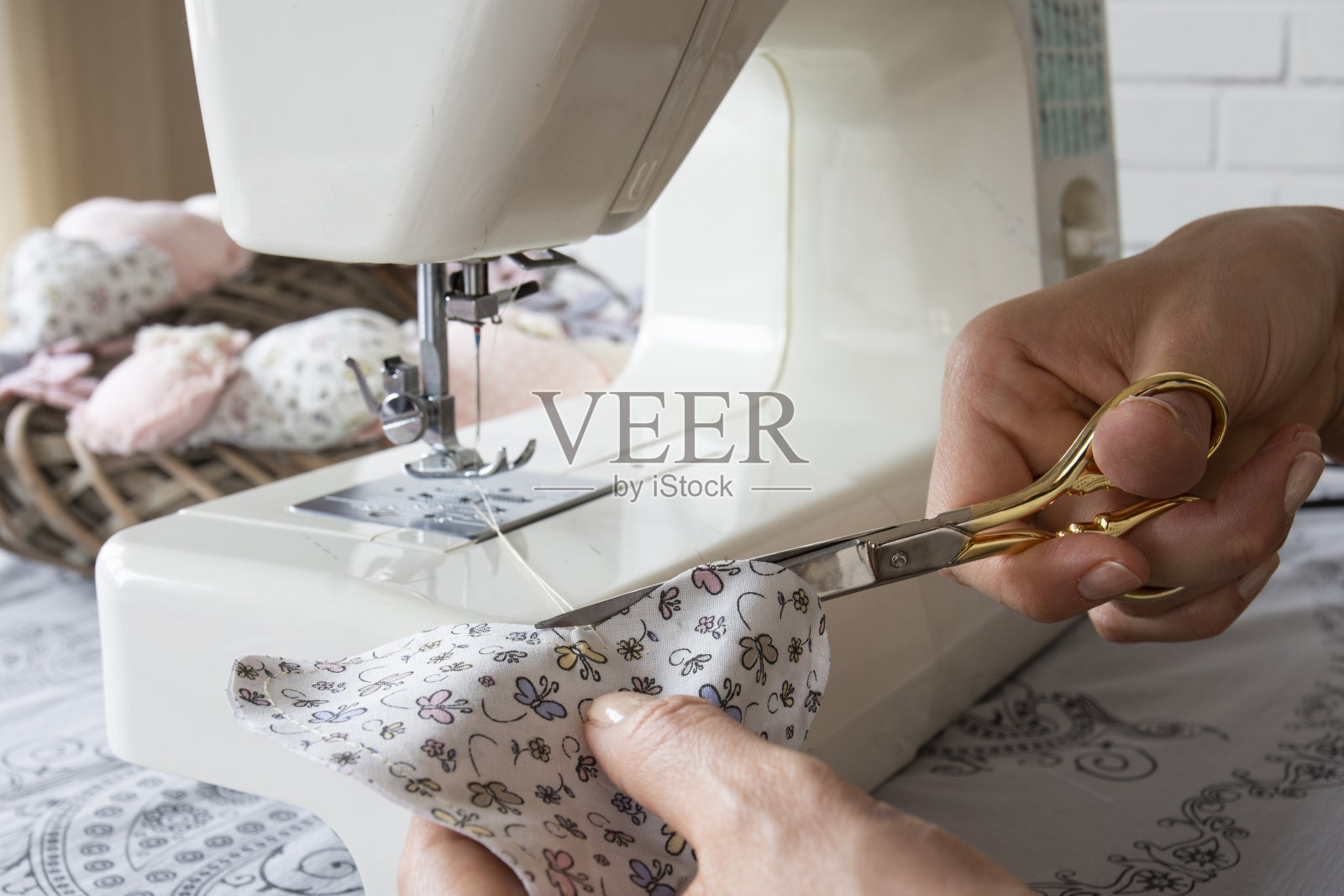 双手在缝纫机上工作。她正在用剪刀剪布照片摄影图片