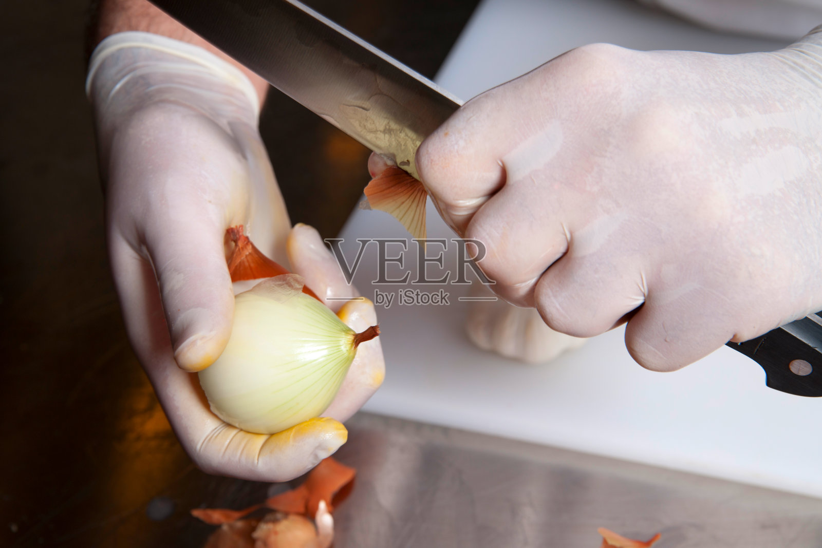 厨师用手套将洋葱从外皮上清洗，以便烹饪照片摄影图片