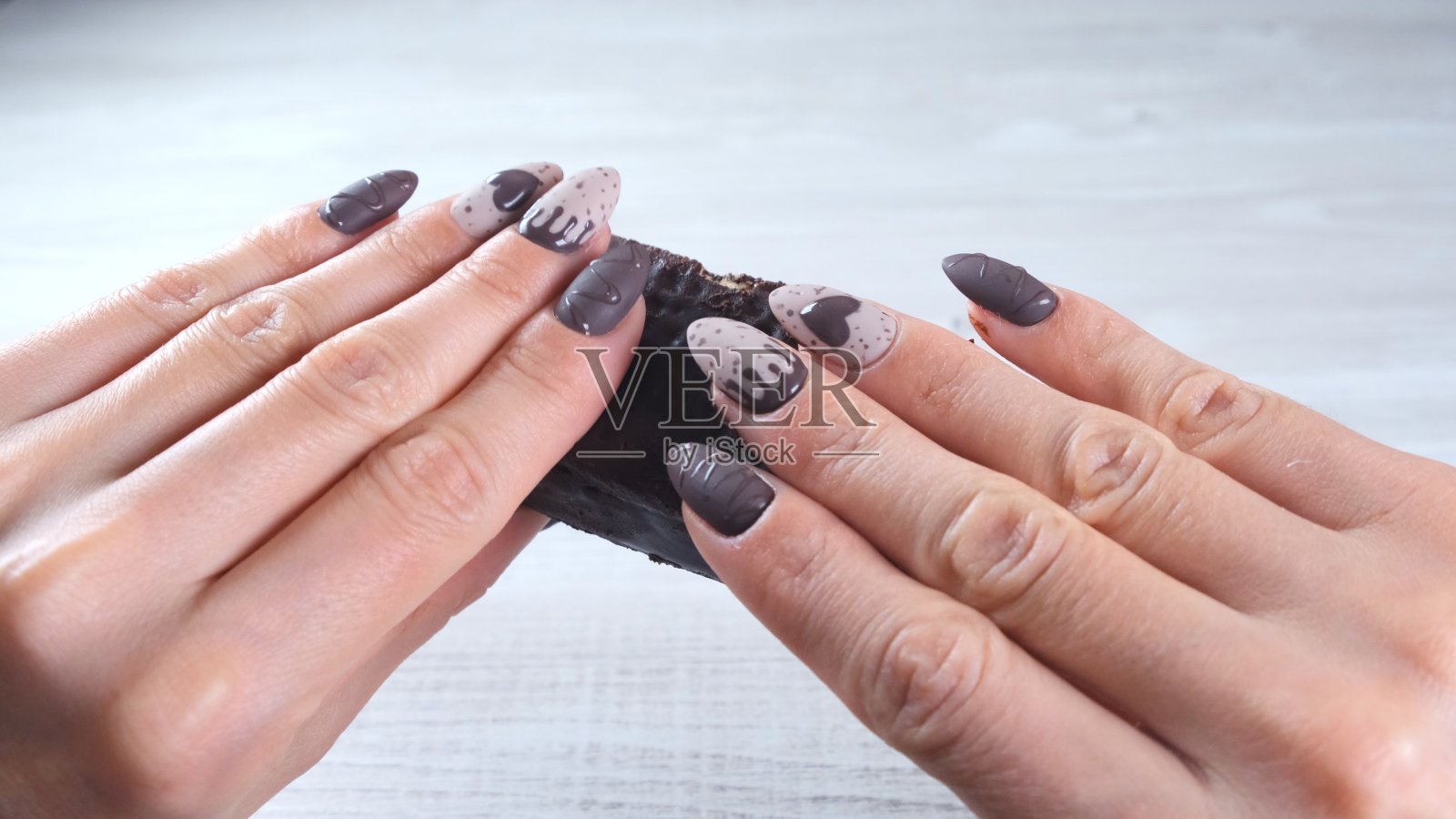 女性的手用美丽的指甲在巧克力糖果的形式，打破一个展开的黑巧克力，特写。喜欢甜点照片摄影图片