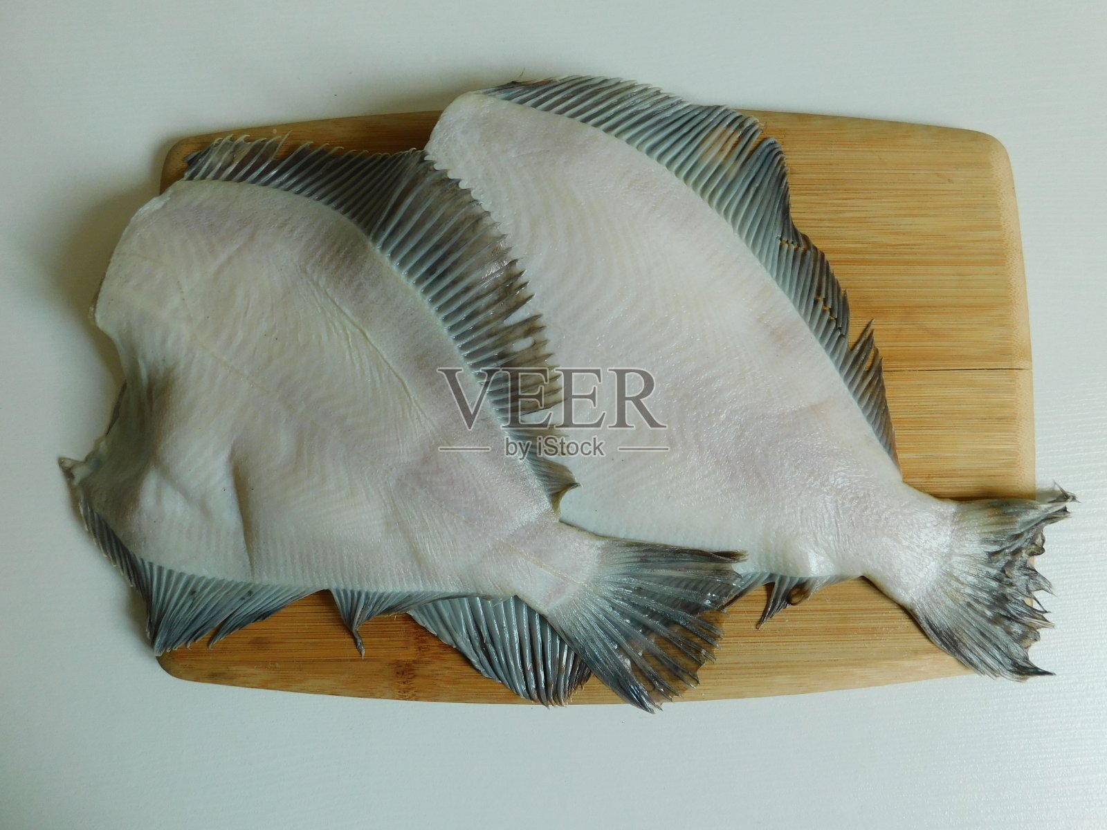 两道新鲜比目鱼，大小不一。照片摄影图片