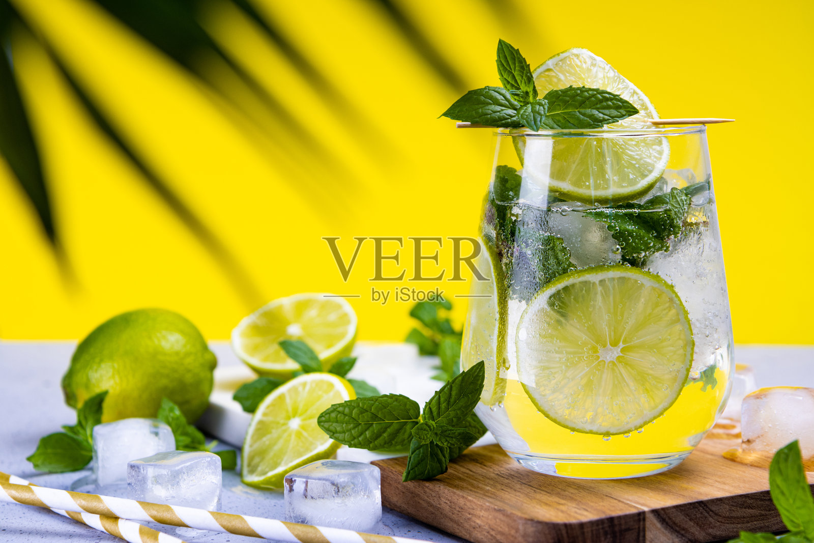 清新的莫吉托，柠檬，薄荷和冰在一个夏天的黄色背景杯。寒冷的夏季鸡尾酒照片摄影图片