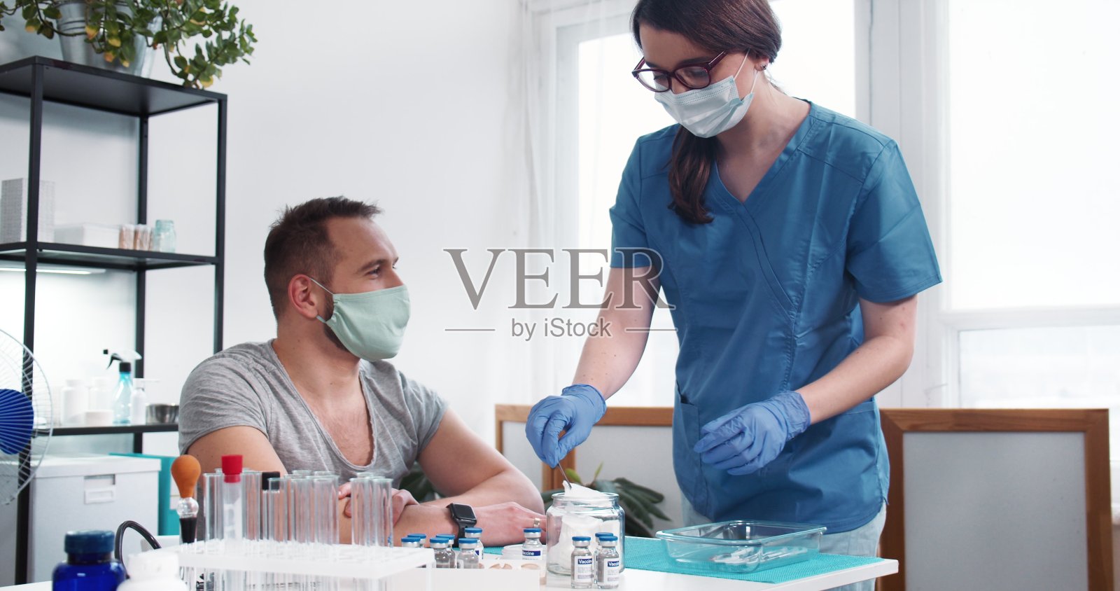 疫苗接种的过程。年轻的护士女医生在诊所给男病人注射疫苗。照片摄影图片