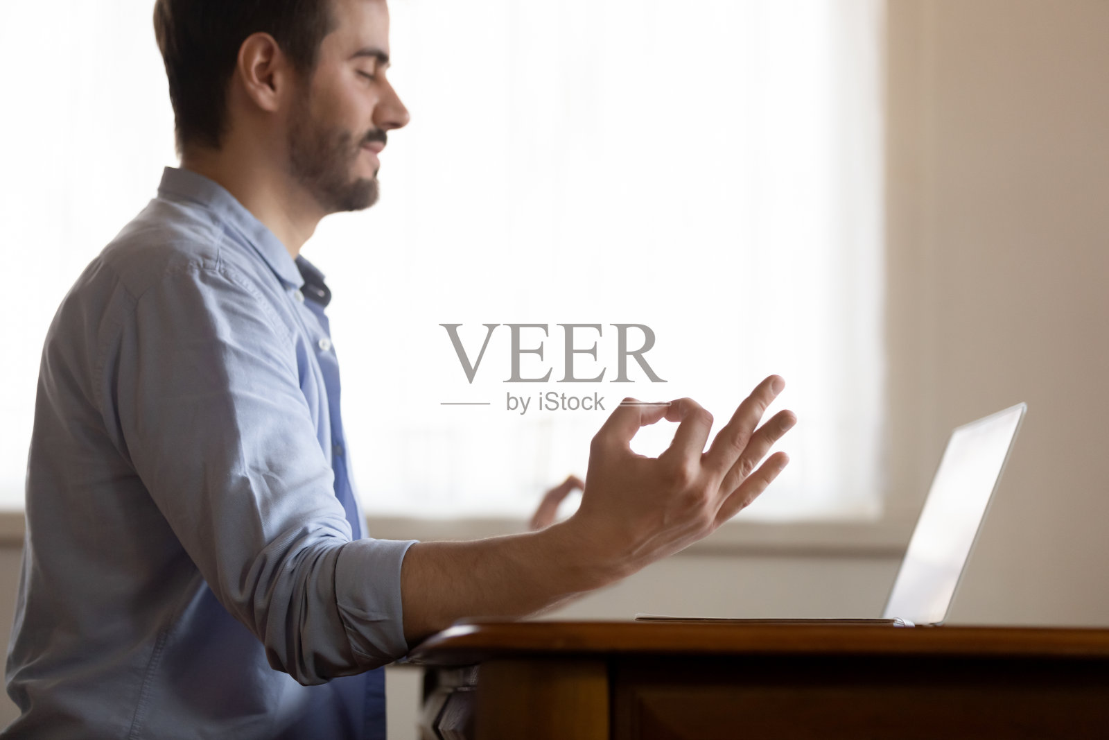 冷静的千禧一代男性远程工作者在工作场所放松练习瑜伽照片摄影图片