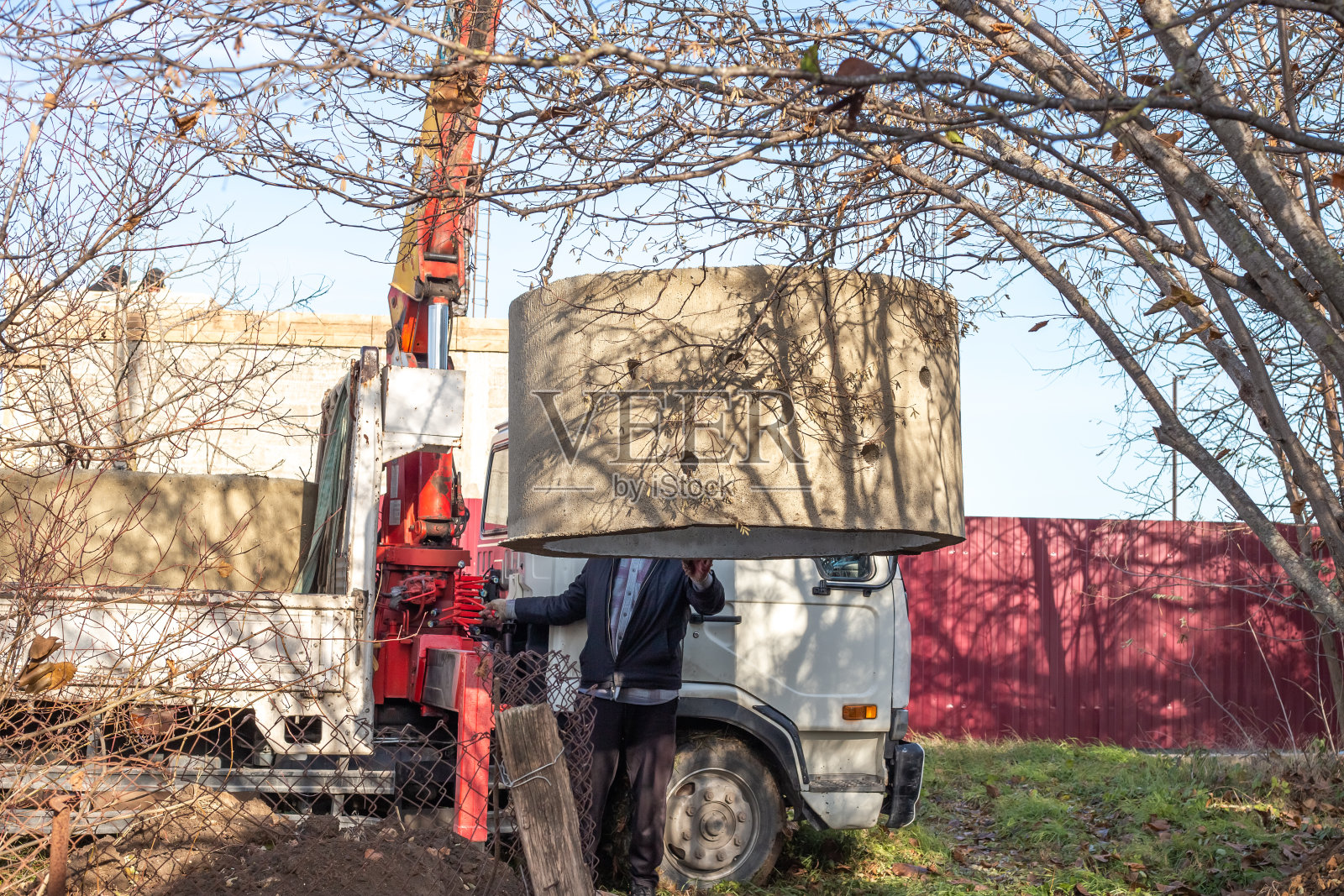 用装载机将直径为1.5米的混凝土环卸入挖好的坑内建造化粪池。在村里安装下水道照片摄影图片