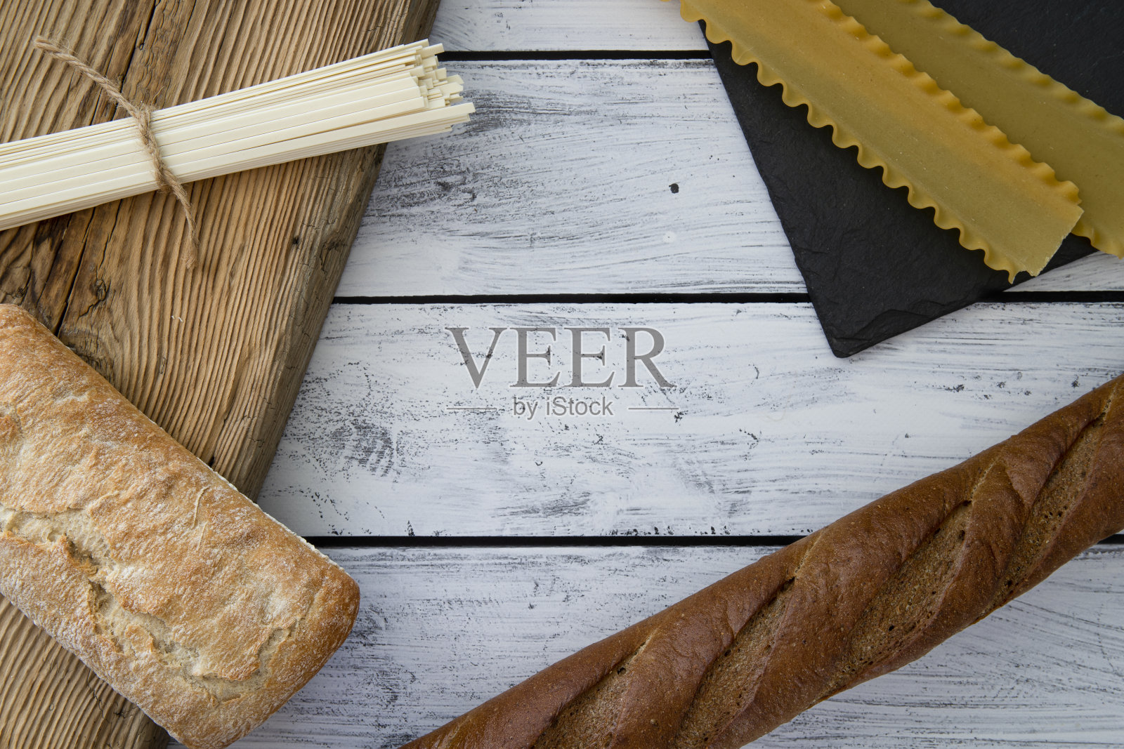 面包，小圆面包，佛卡夏，夏巴塔，乌冬，意大利面，面粉产品在一个木制的背景。地中海厨房。俯视图照片摄影图片