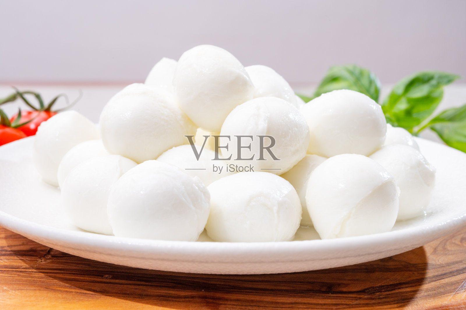 意大利三色奶酪，新鲜的白色软意大利马苏里拉奶酪小球，成熟的红色樱桃番茄和新鲜的绿色罗勒香草，准备做卡普里沙拉照片摄影图片