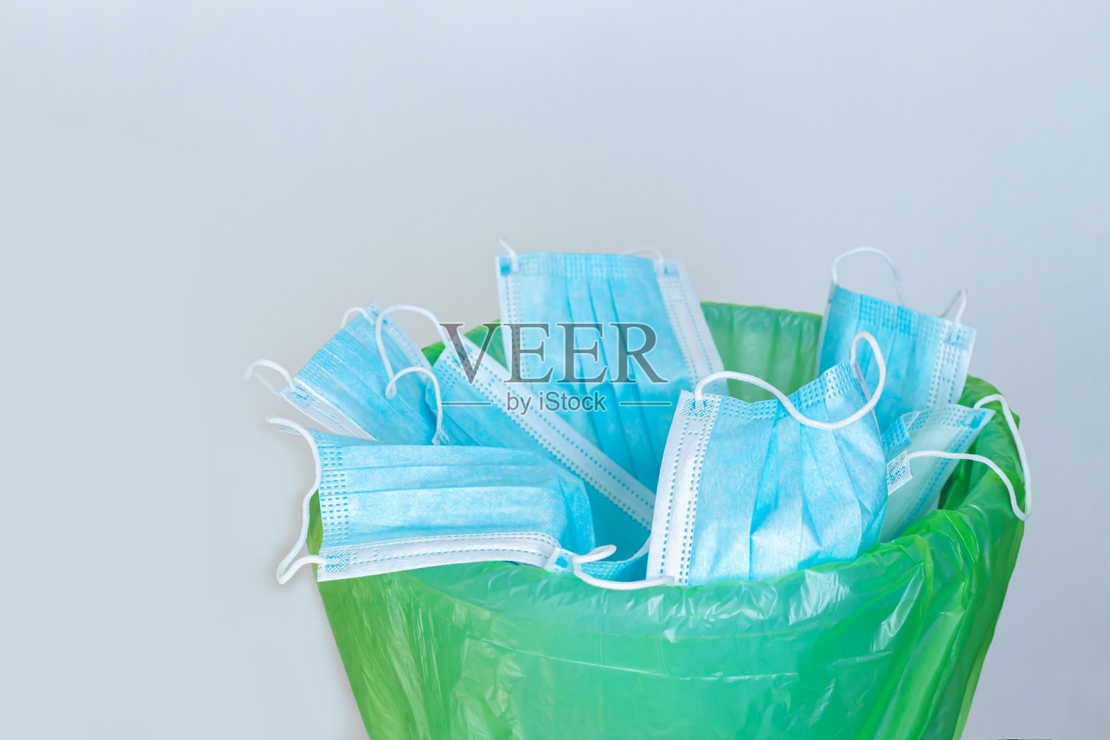 使用过的传染性口罩扔进垃圾桶或丢弃的一次性外科口罩照片摄影图片