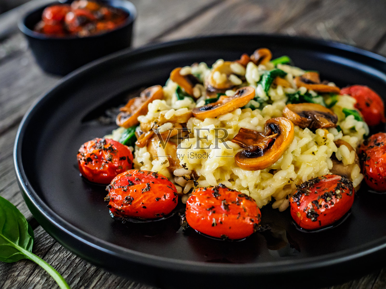木桌上的白蘑菇、烤番茄和帕尔马干酪烩饭照片摄影图片
