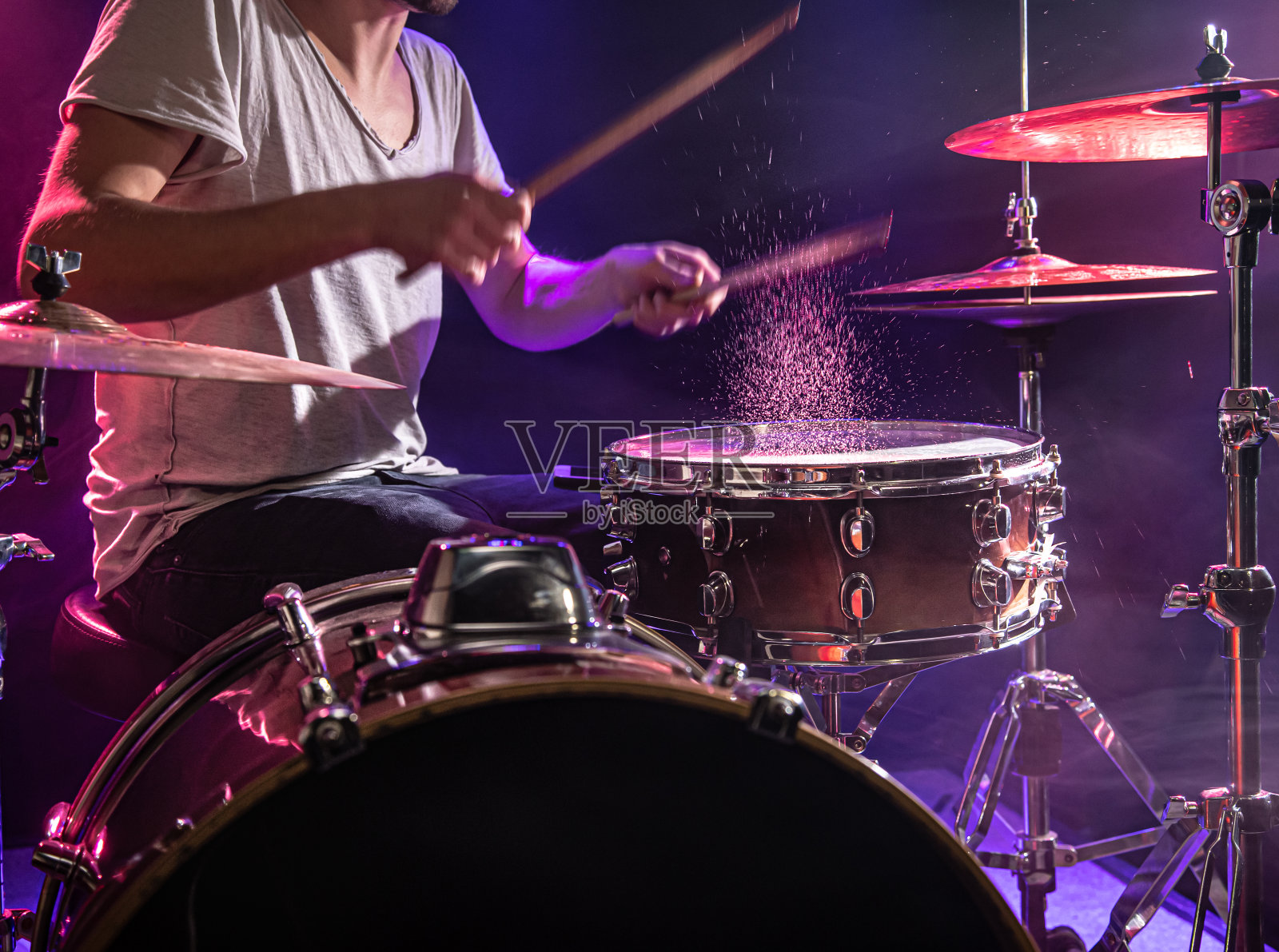 鼓手打鼓。美丽的蓝色和红色背景，与光线。美丽的特效烟雾和灯光。演奏乐器的过程特写照片。照片摄影图片