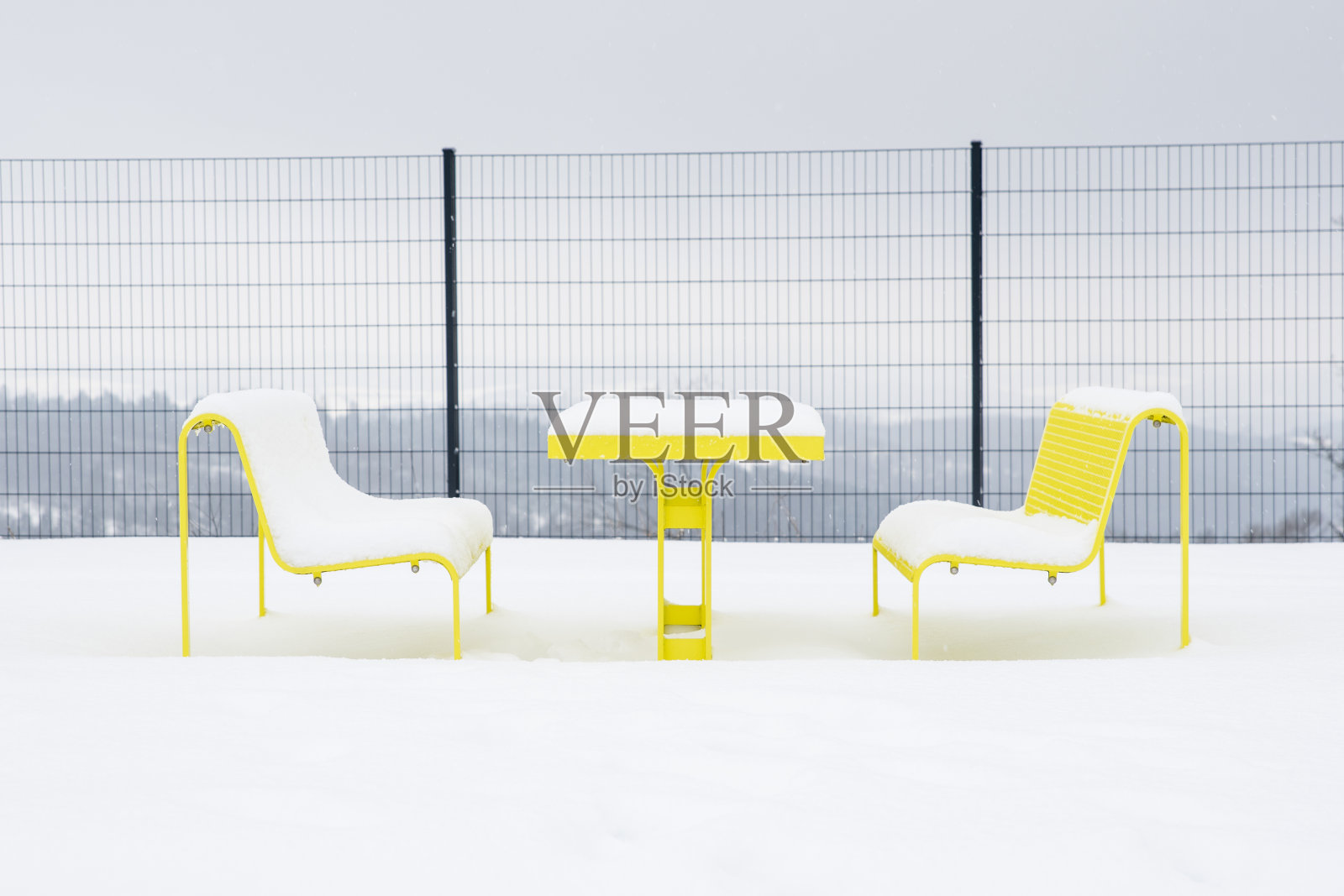 德国高速公路休息区，黄色金属座椅被雪覆盖。照片摄影图片
