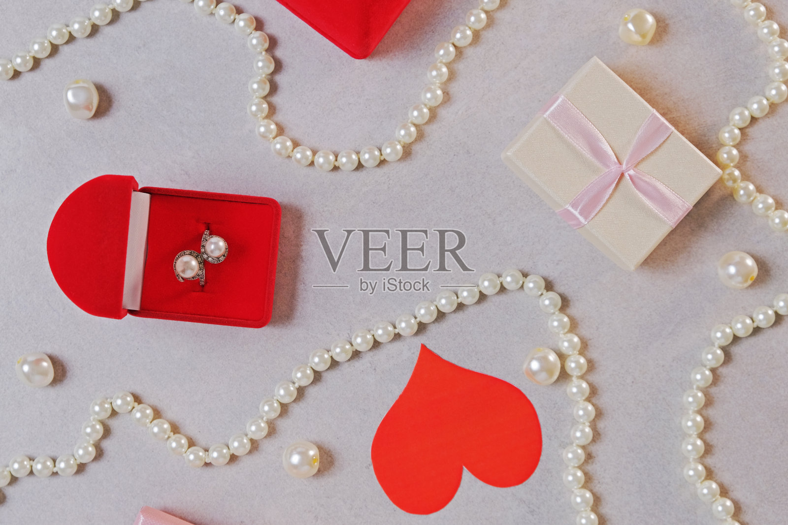 红盒子里的金戒指和珍珠。情人节的浪漫背景有宝石、礼物、订婚戒指等。求婚、婚礼或节日礼物的概念。贺卡照片摄影图片