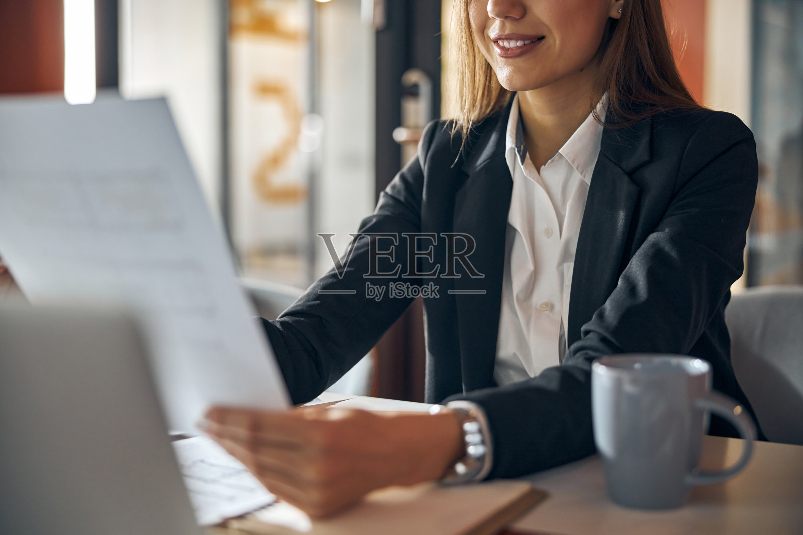 拿着一张纸坐在桌子前的女人照片摄影图片