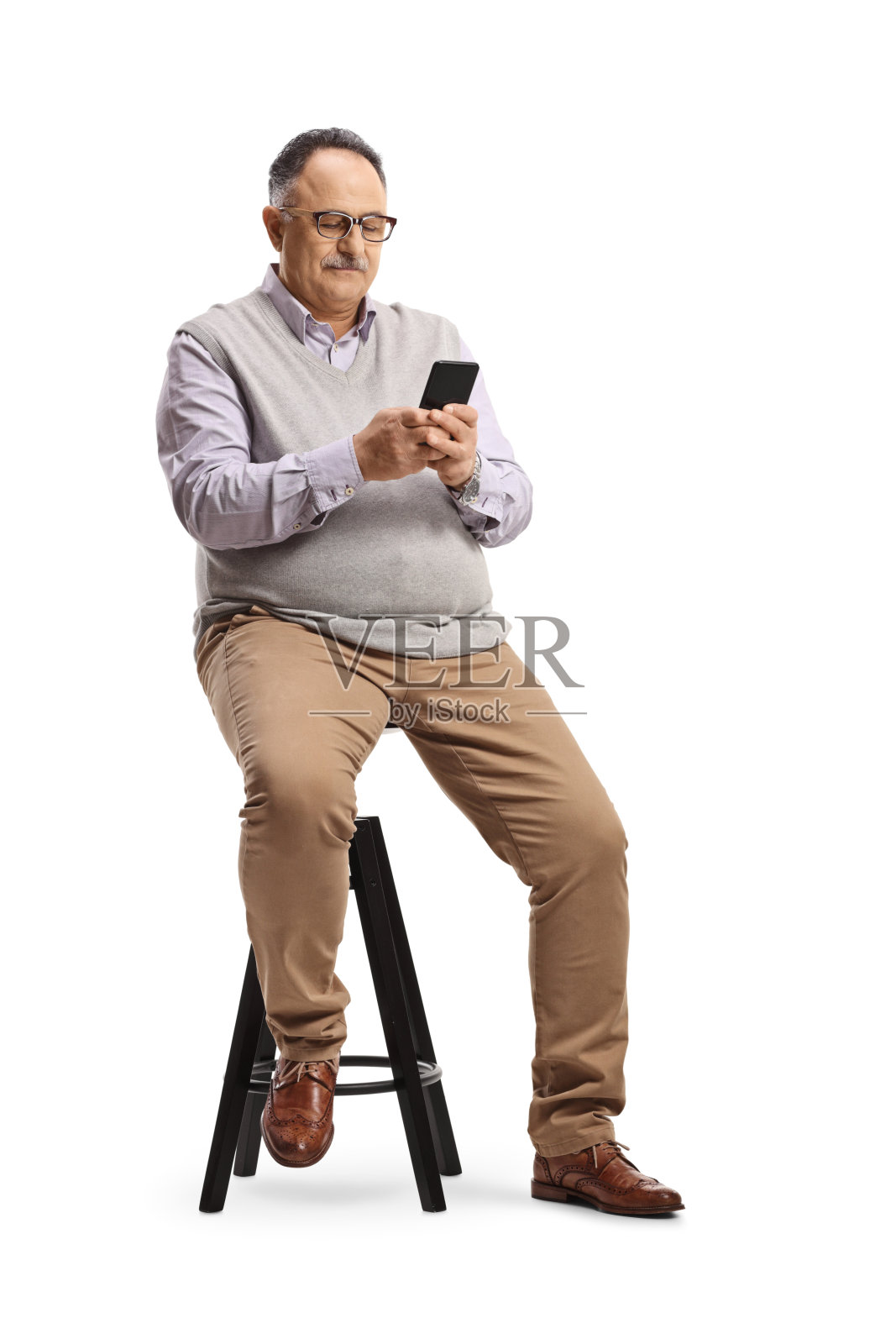 年长的男人坐在椅子上用手机打字照片摄影图片