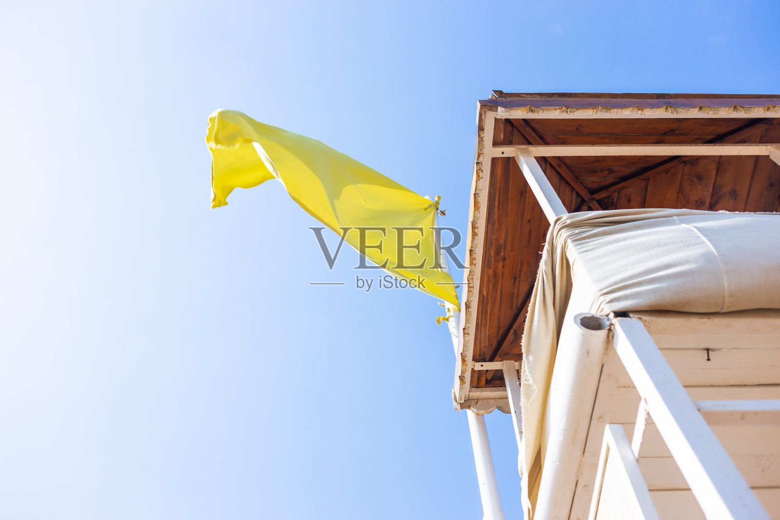 白色的，木制的空的救援塔在海边荒凉的海滩上，黄色的警示旗照片摄影图片