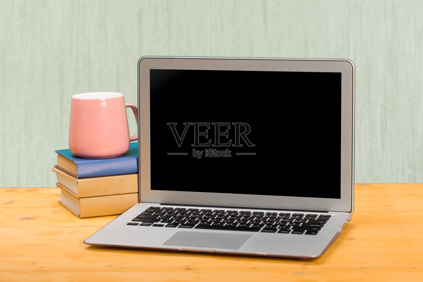 一台笔记本电脑，一个空白的屏幕用来展示产品，一张木桌和一面墙上放着一杯咖啡。模型照片摄影图片