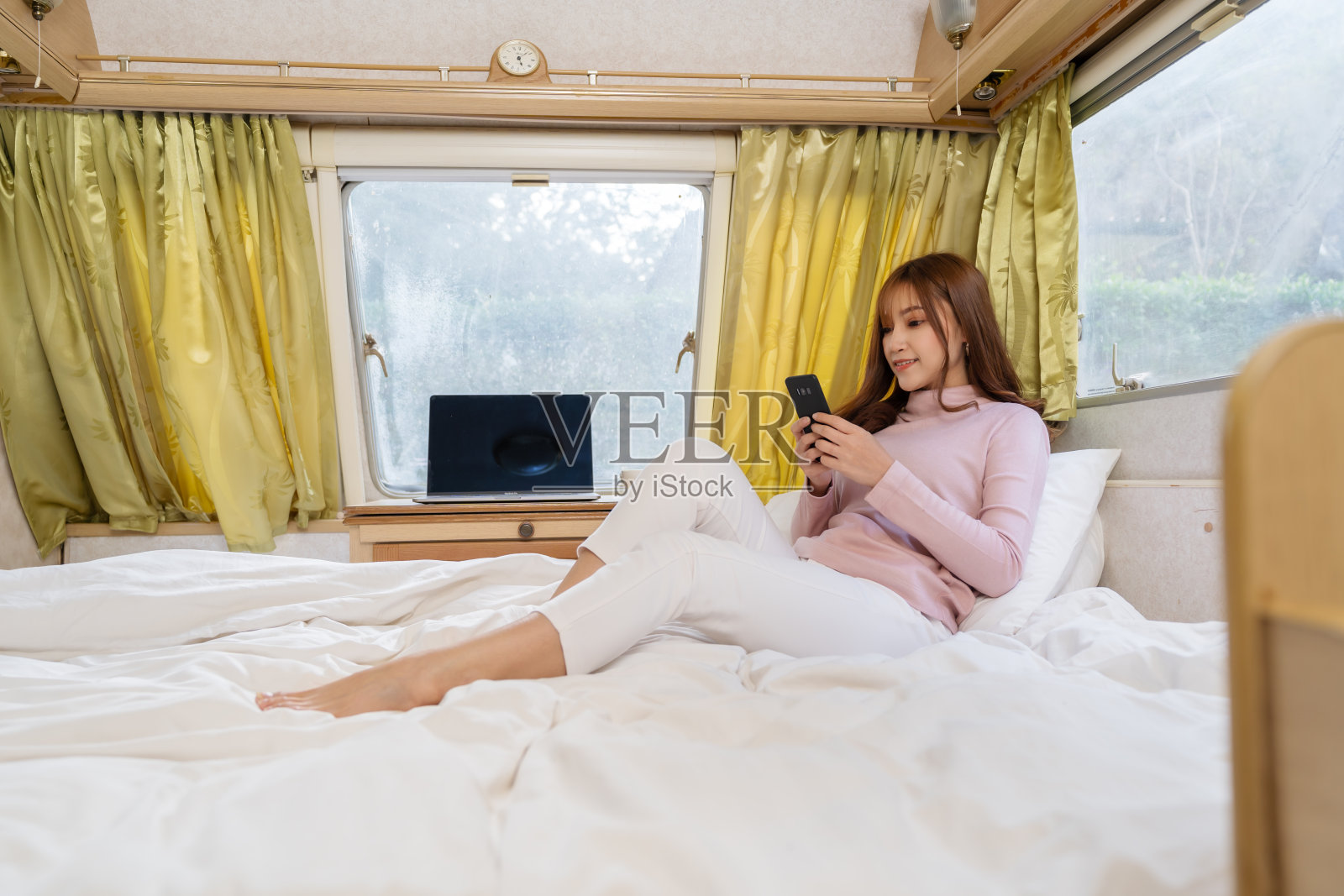 一名女子在露营房车房车房车的床上使用智能手机照片摄影图片