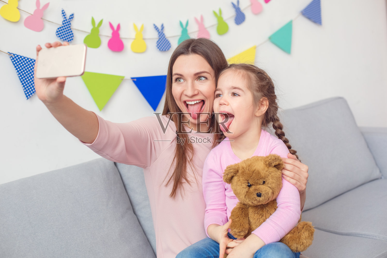 母亲和女儿一起周末在家坐着用智能手机自拍照片摄影图片