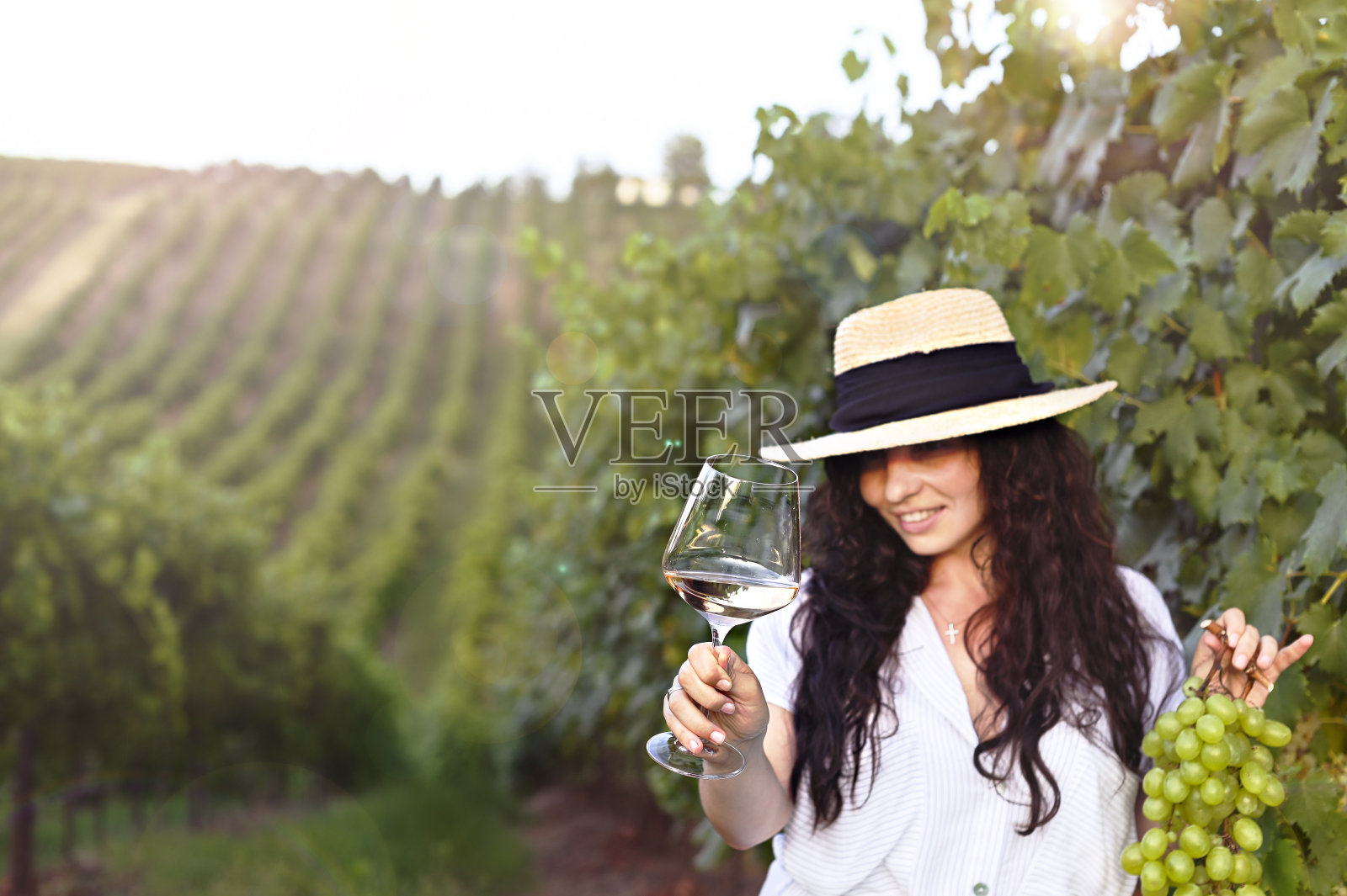 在意大利的葡萄园里喝着白葡萄酒的年轻女子。人倒酒。文本的空闲空间照片摄影图片