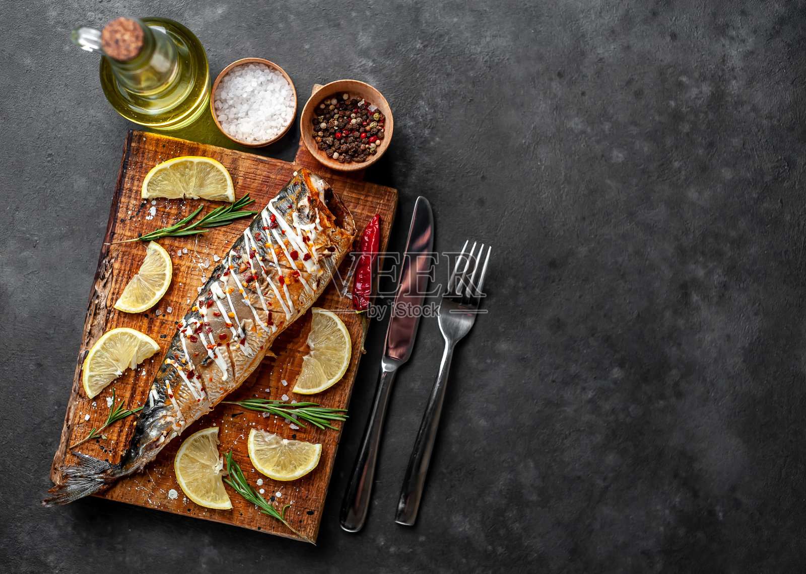 烤鲭鱼在切菜板上与柠檬和香料在石头背景，为你的文本复制空间照片摄影图片