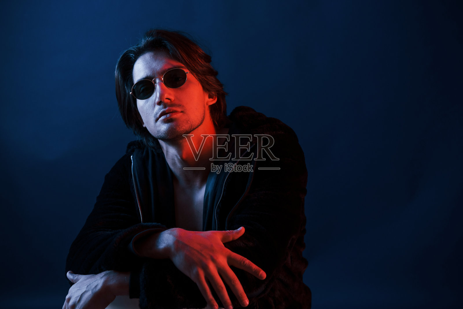 戴着眼镜，穿着黑衣服的帅哥在录音棚里，还有蓝色的霓虹灯照片摄影图片