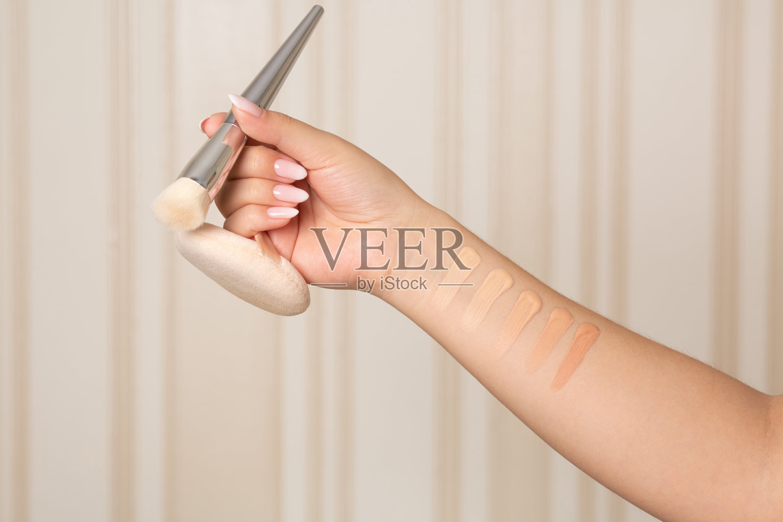 女性的手拿着化妆刷和粉扑的色块照片摄影图片